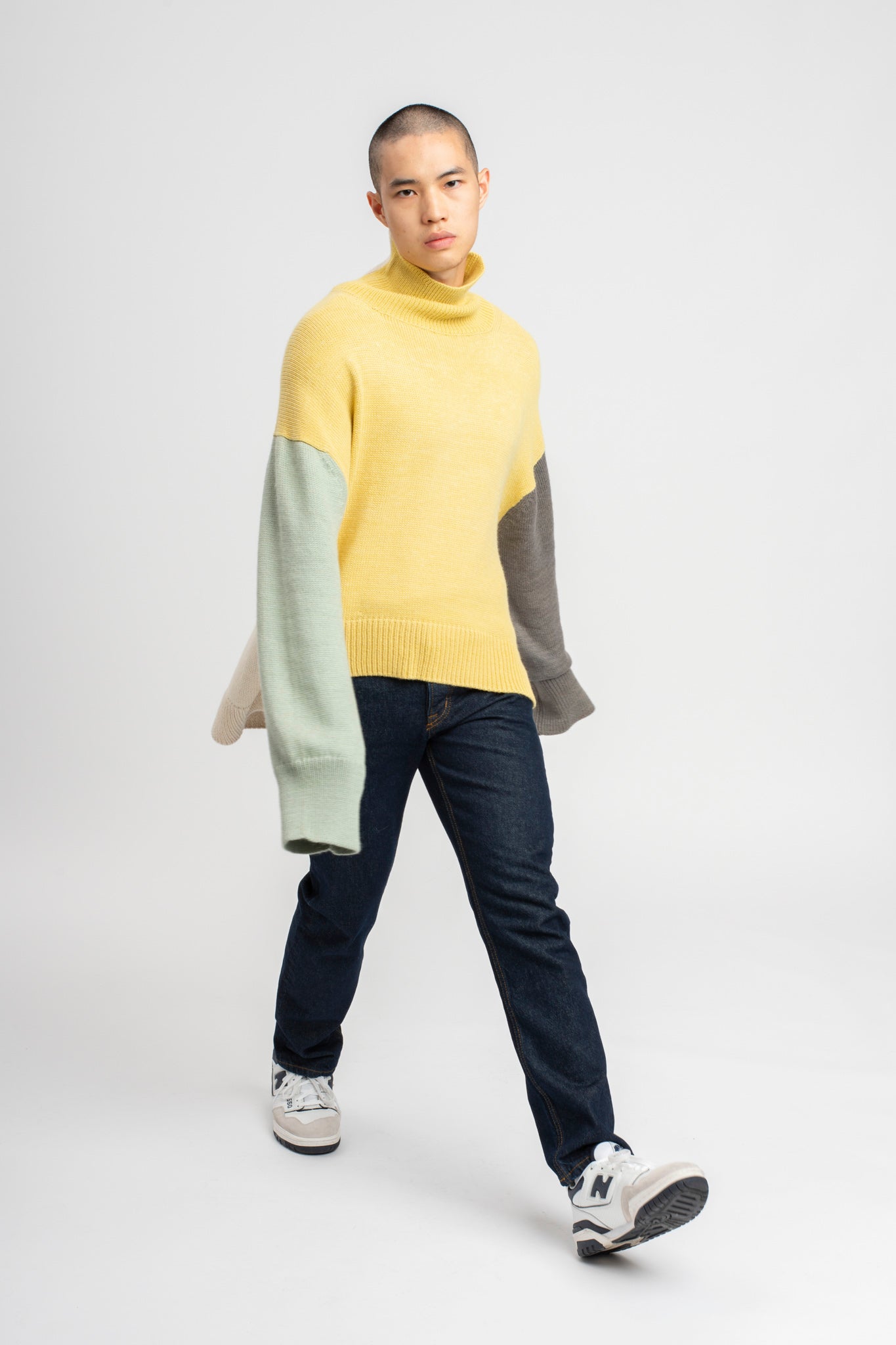 Model wearing turtleneck oversized sweater in multi-color yellow alpaca wool, walking