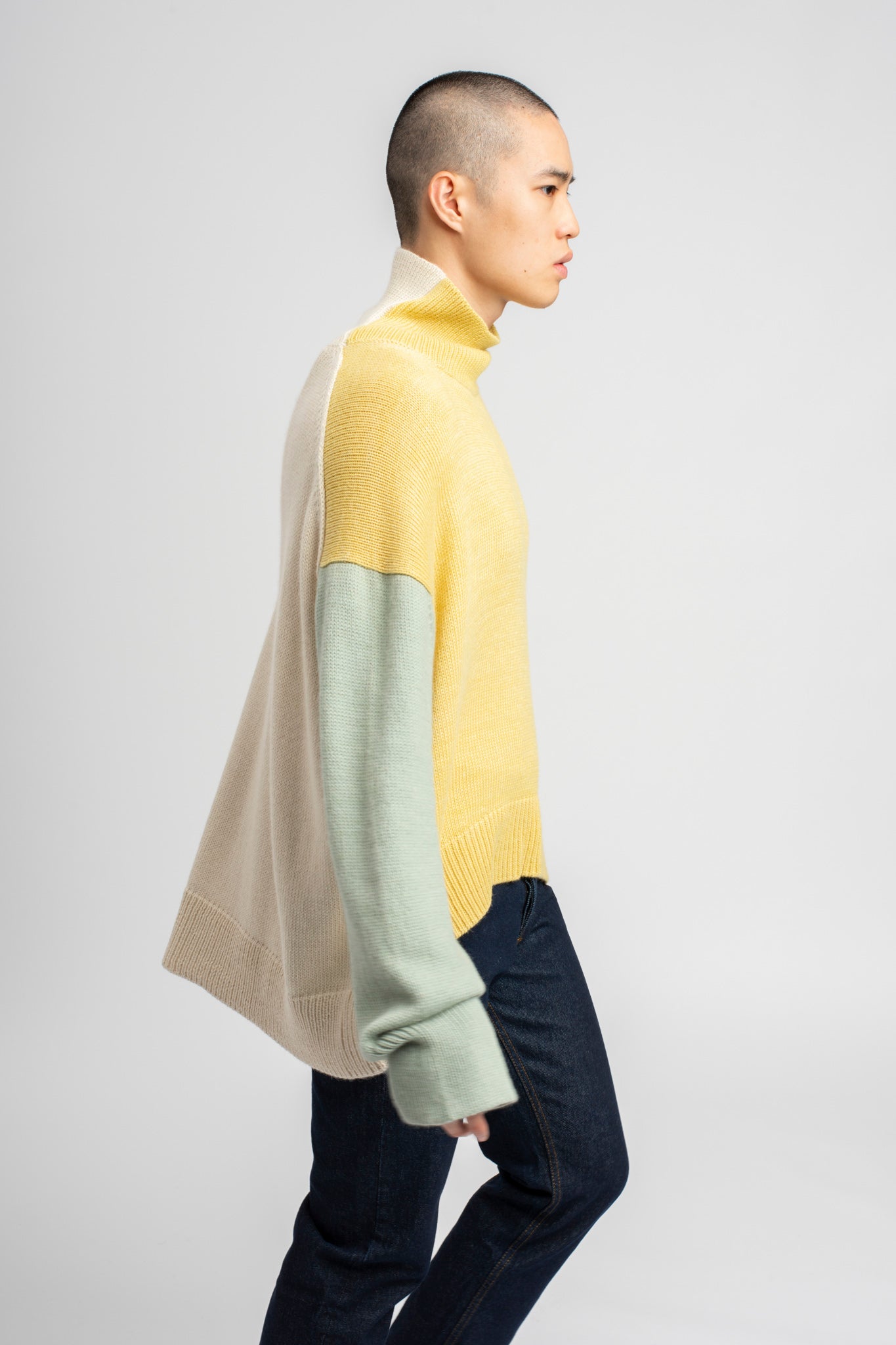 Model wearing turtleneck oversized sweater in multi-color yellow alpaca wool, side