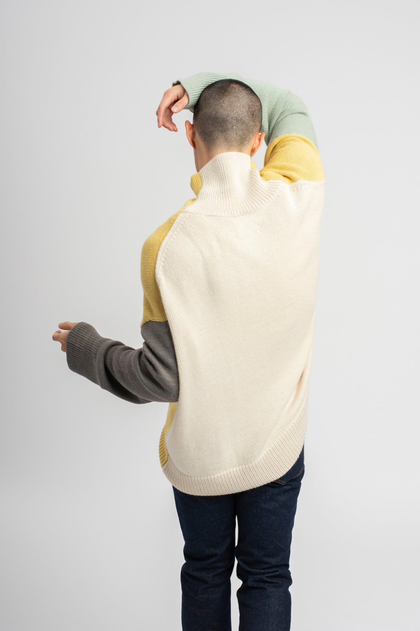 Model wearing turtleneck oversized sweater in multi-color yellow alpaca wool, back