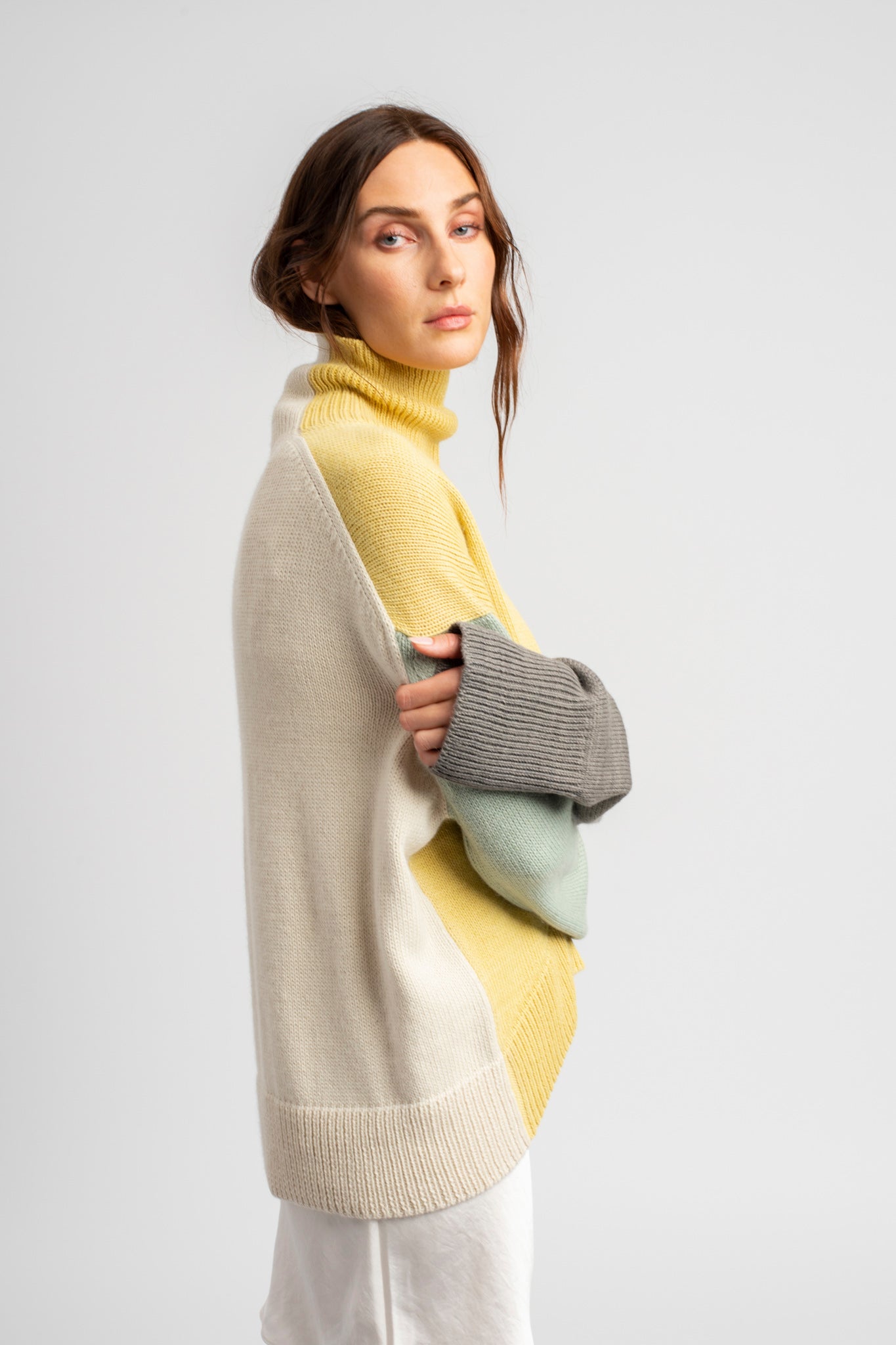 Model wearing turtleneck oversized sweater in multi-color yellow alpaca wool, side close-up