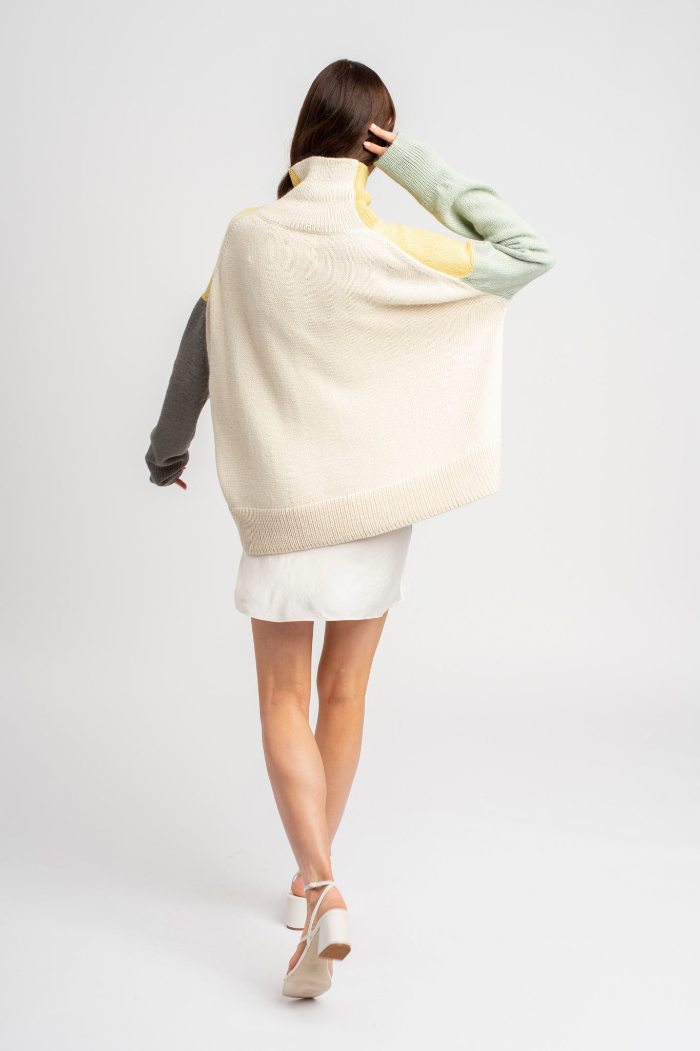 Model wearing turtleneck oversized sweater in multi-color yellow alpaca wool, standing back