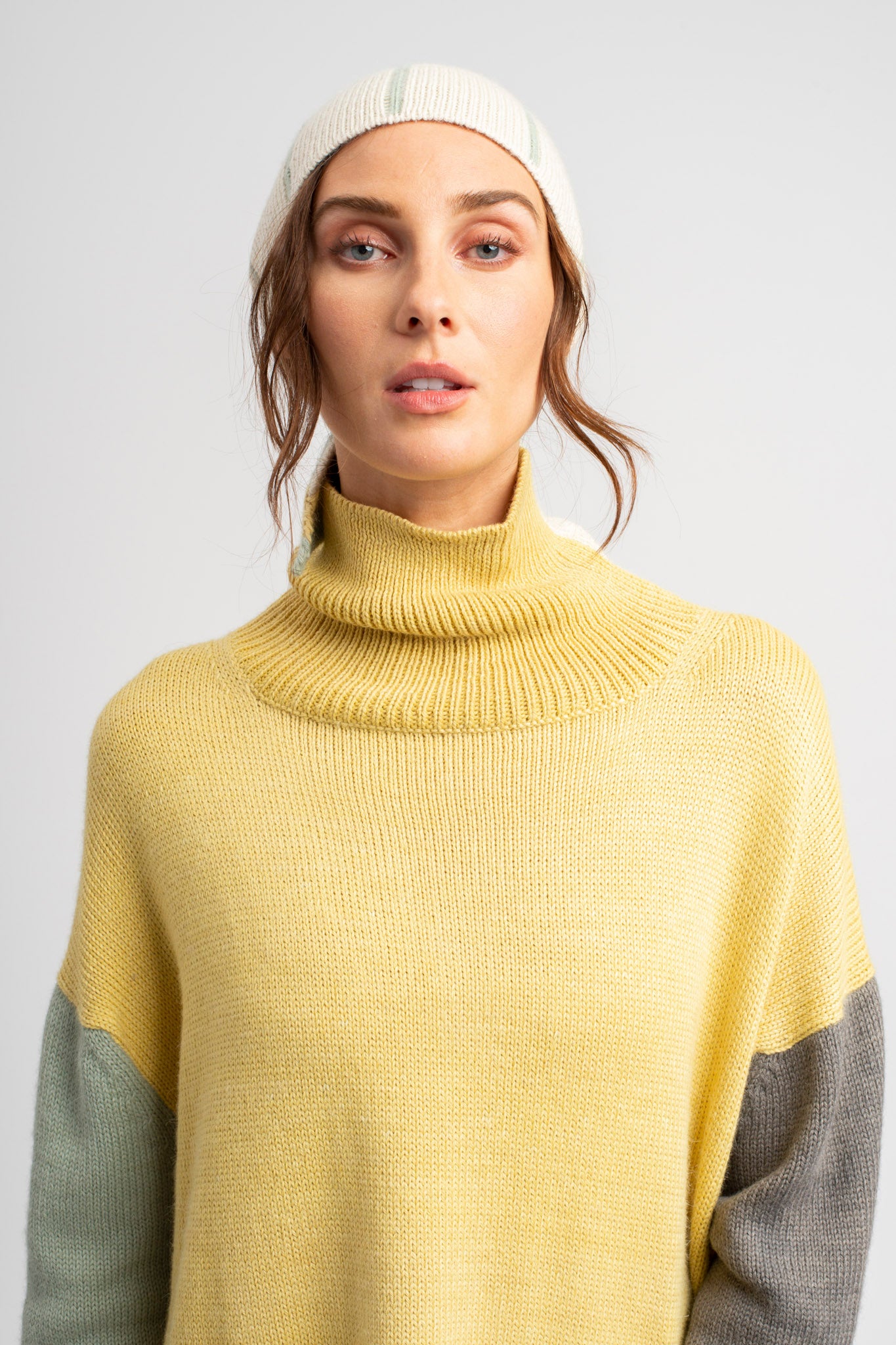 Model wearing turtleneck oversized sweater in multi-color yellow alpaca wool, front close-up