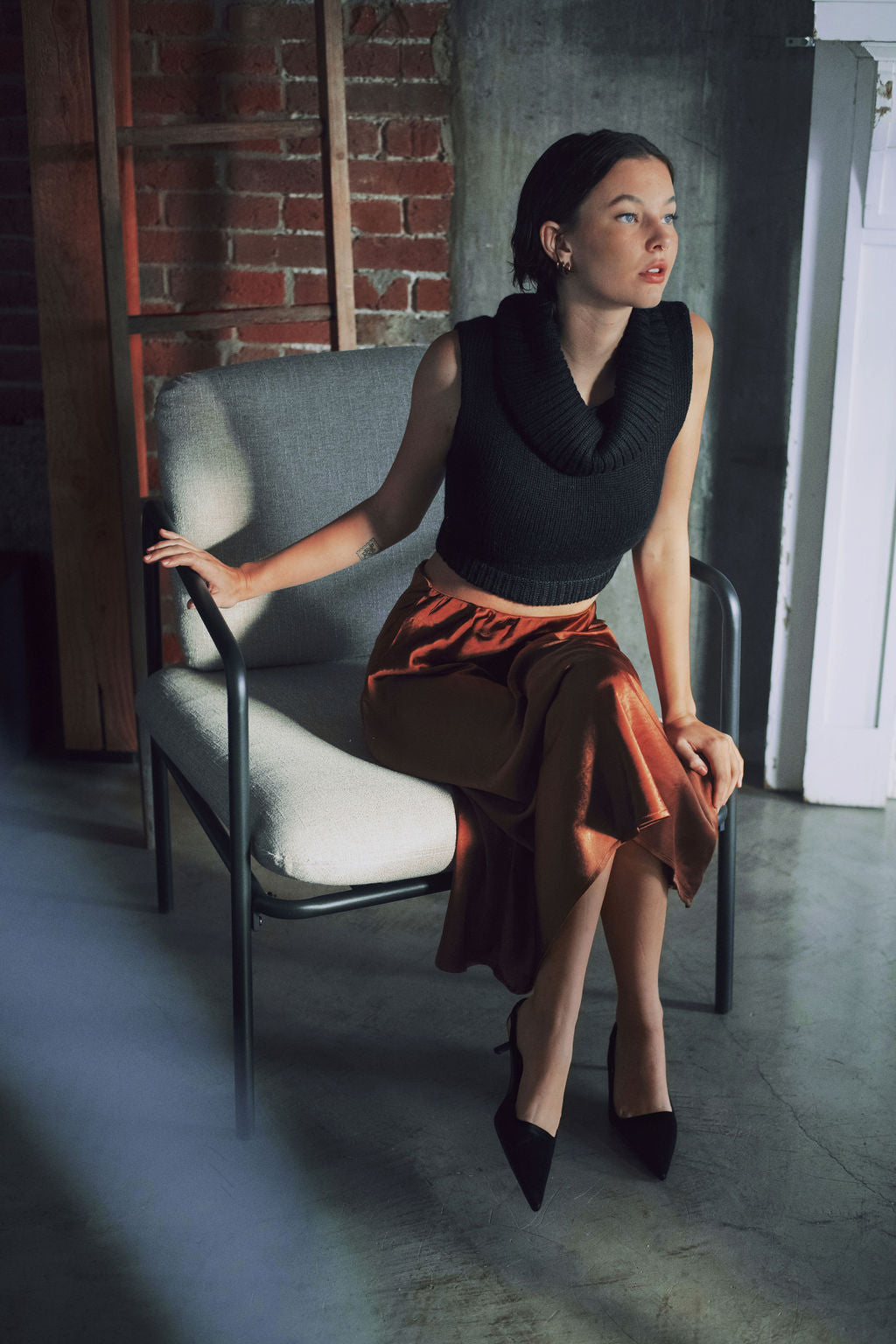 Model wearing black sweater crop top in alpaca wool, sitting down