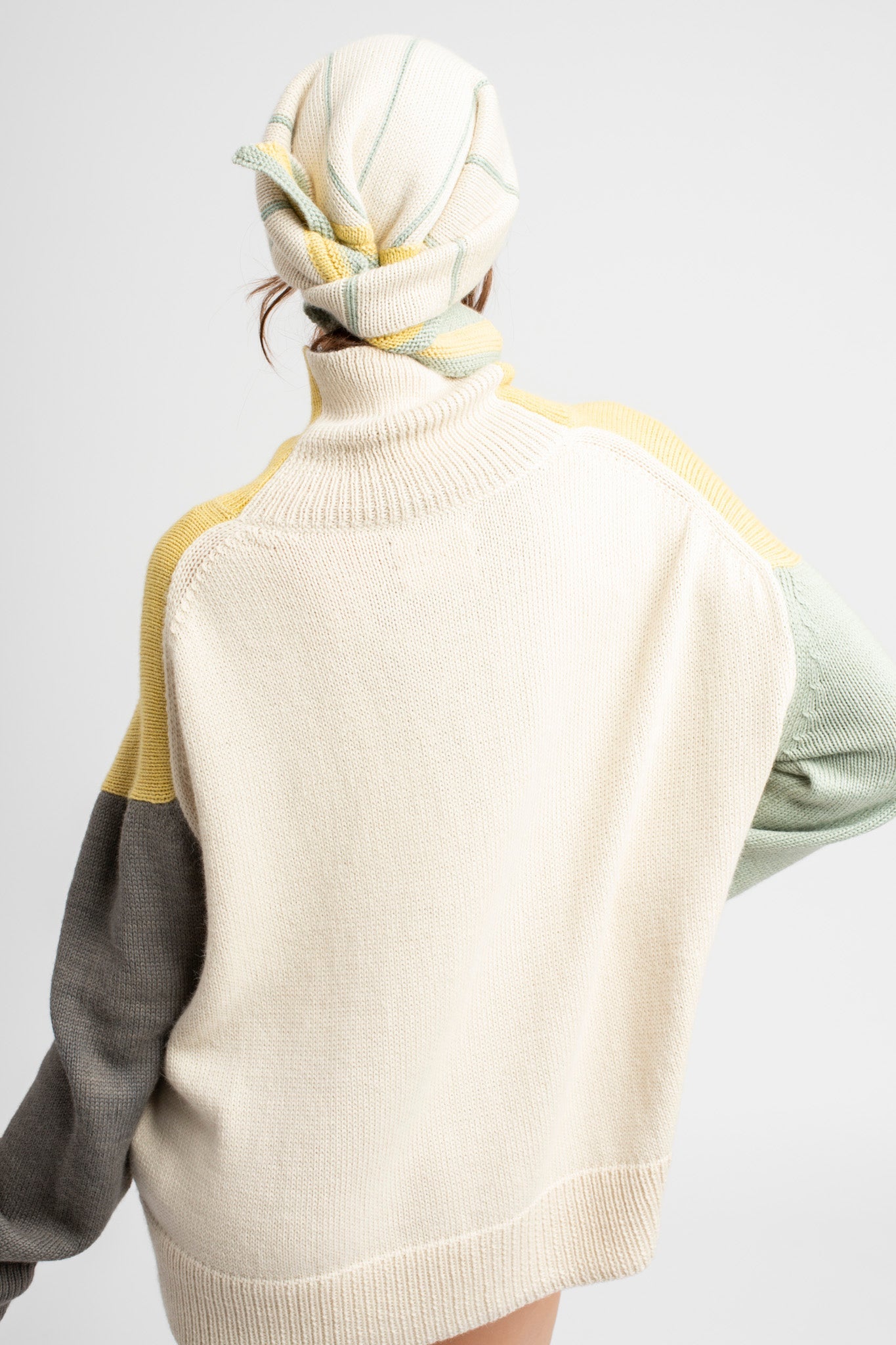 Model wearing knitwear headscarf alpaca wool in white & sage reversible stripes with oversized sweater, back