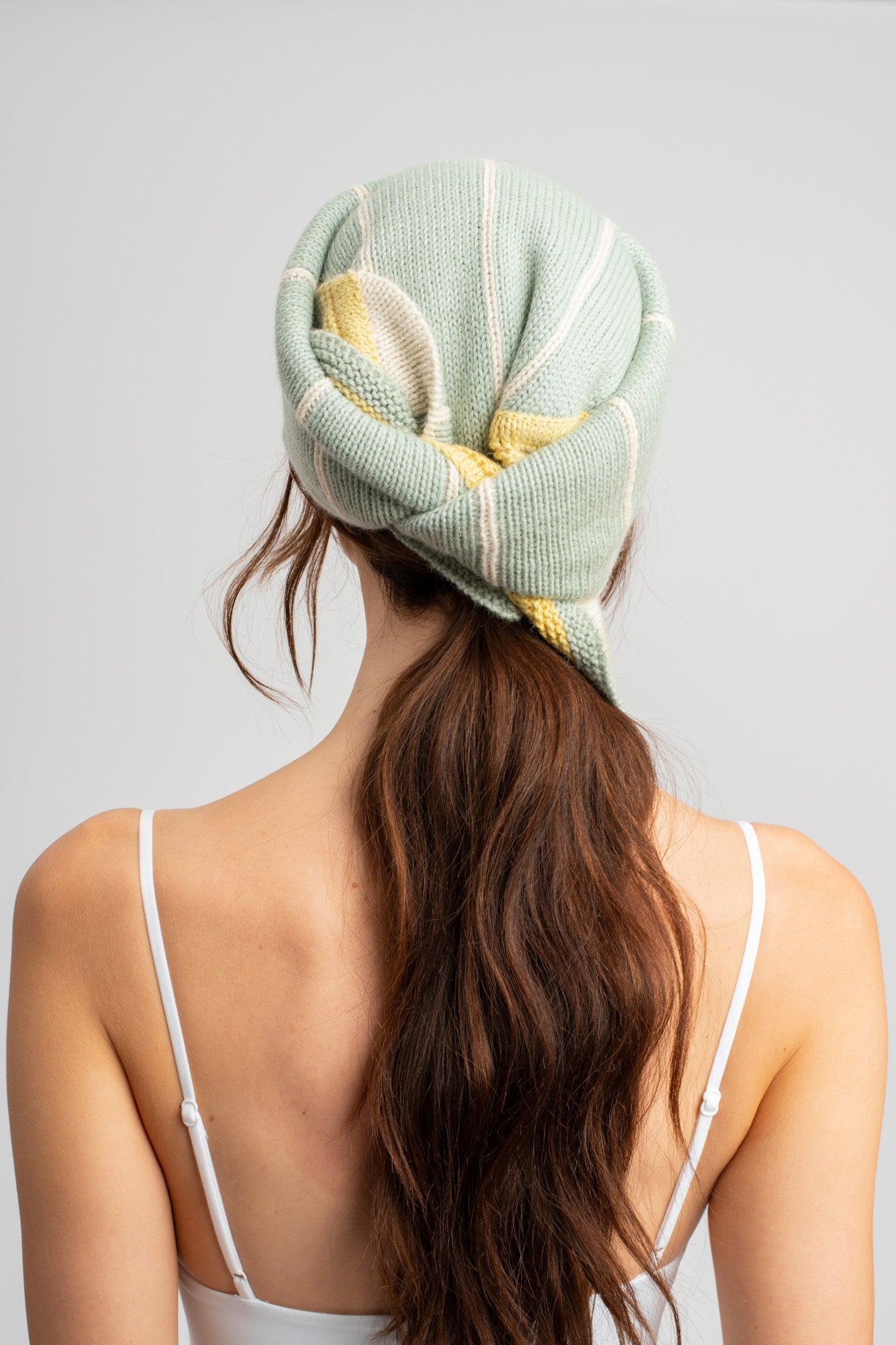 Model wearing knitwear headscarf alpaca wool in white & sage reversible stripes, back