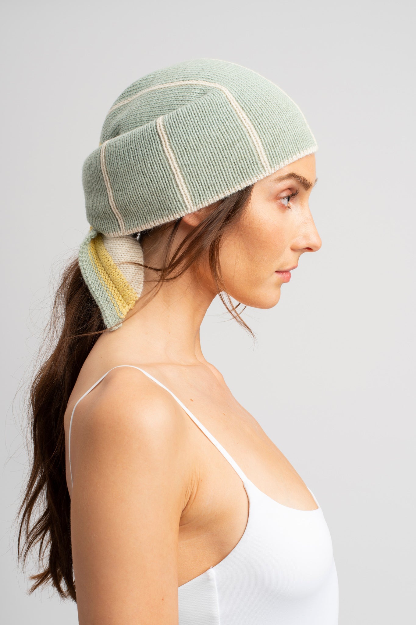 Model wearing knitwear headscarf alpaca wool in white & sage reversible stripes, side