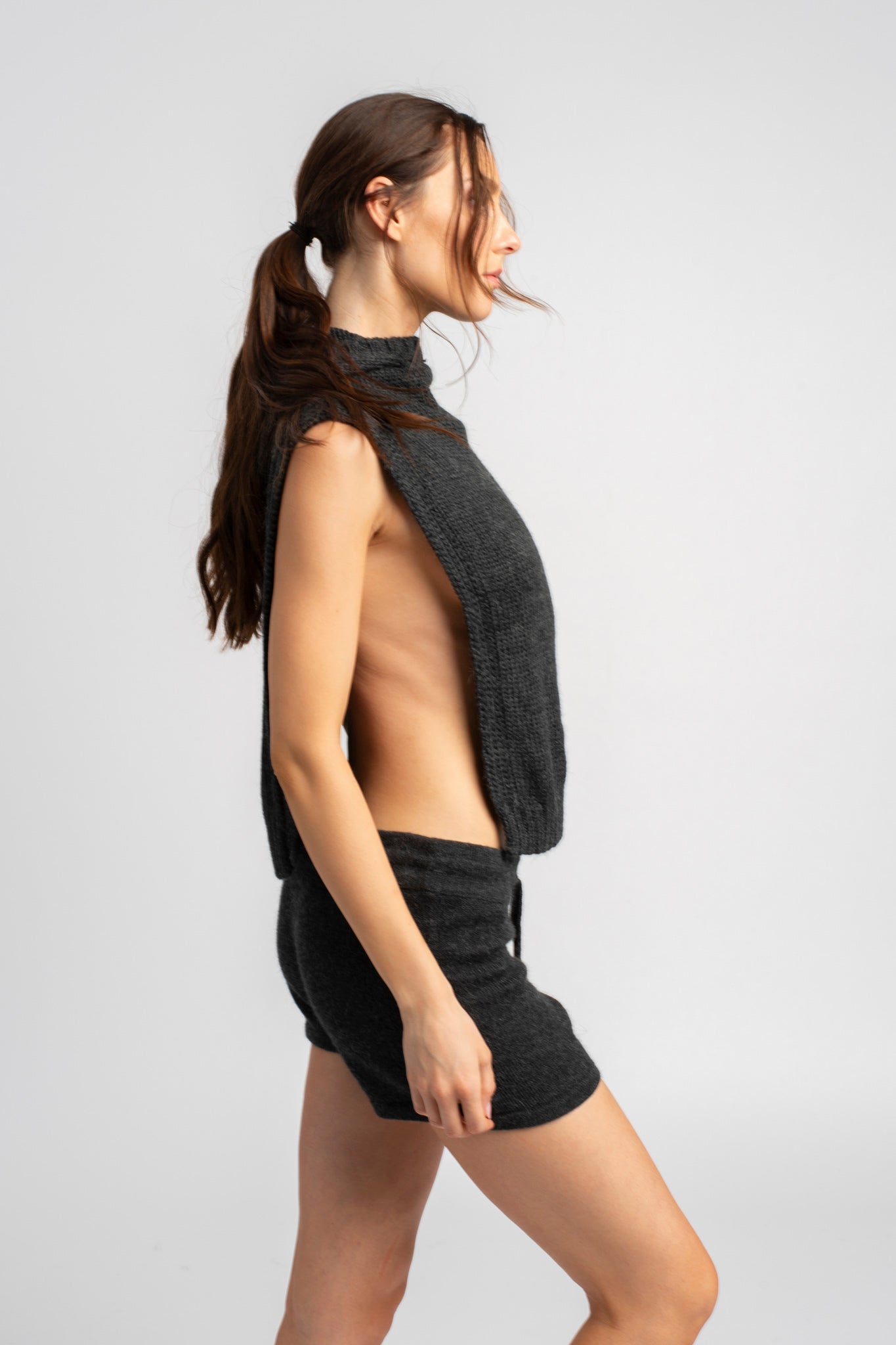 Model wearing knitwear alpaca wool dark grey shorts with matching knit poncho, side