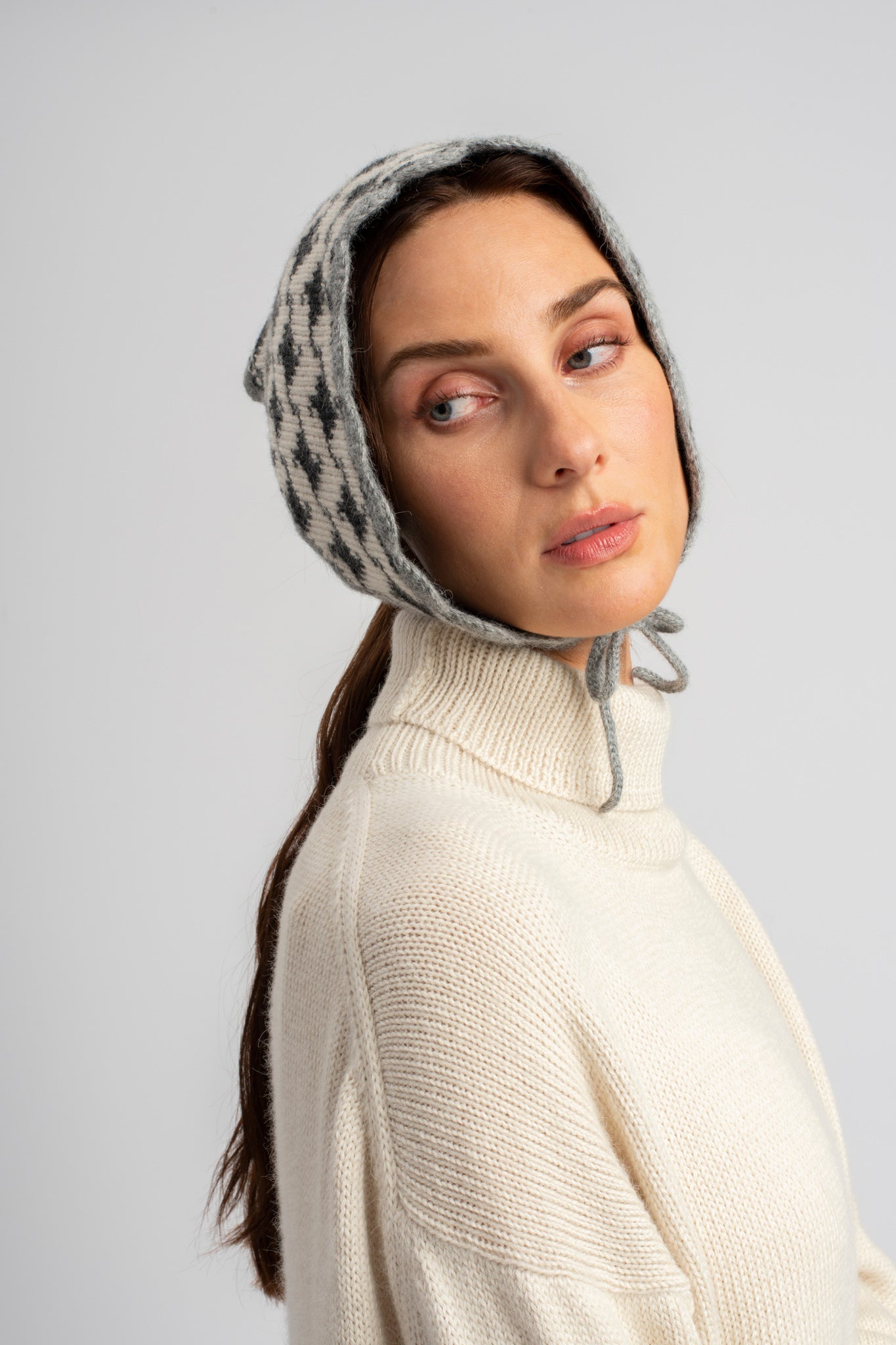 Model wearing knitwear alpaca wool headscarf in white & grey reversible houndstooth with white sweater