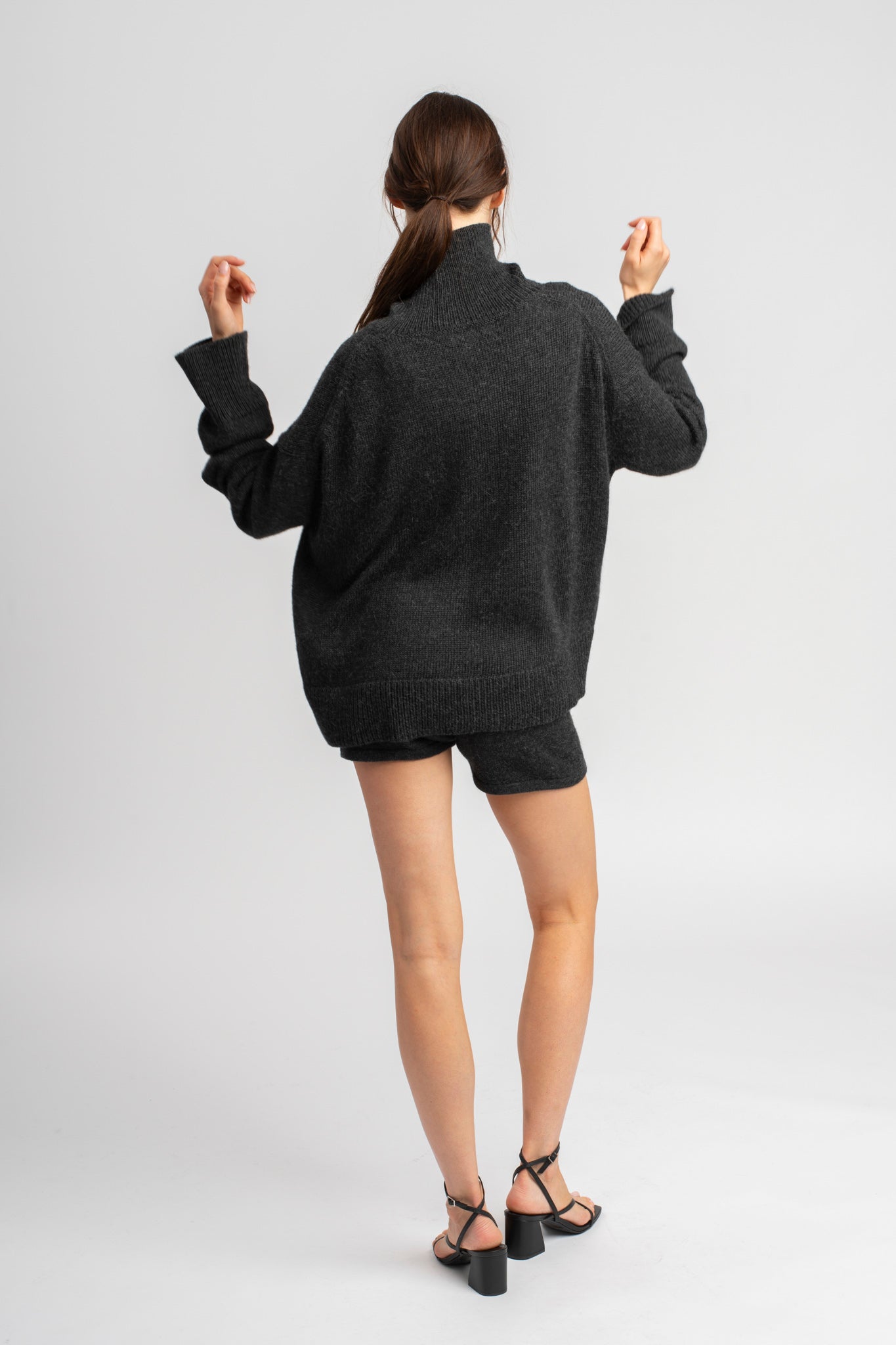 Model wearing knitwear alpaca wool dark grey shorts and oversized sweater, back