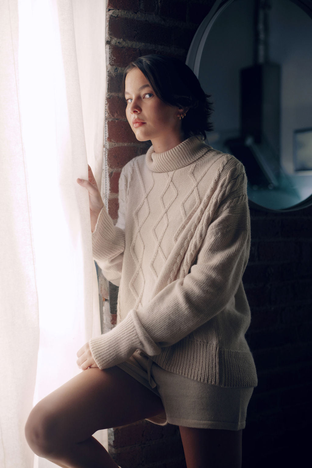 Model wearing oversized cable sweater in white alpaca wool, side