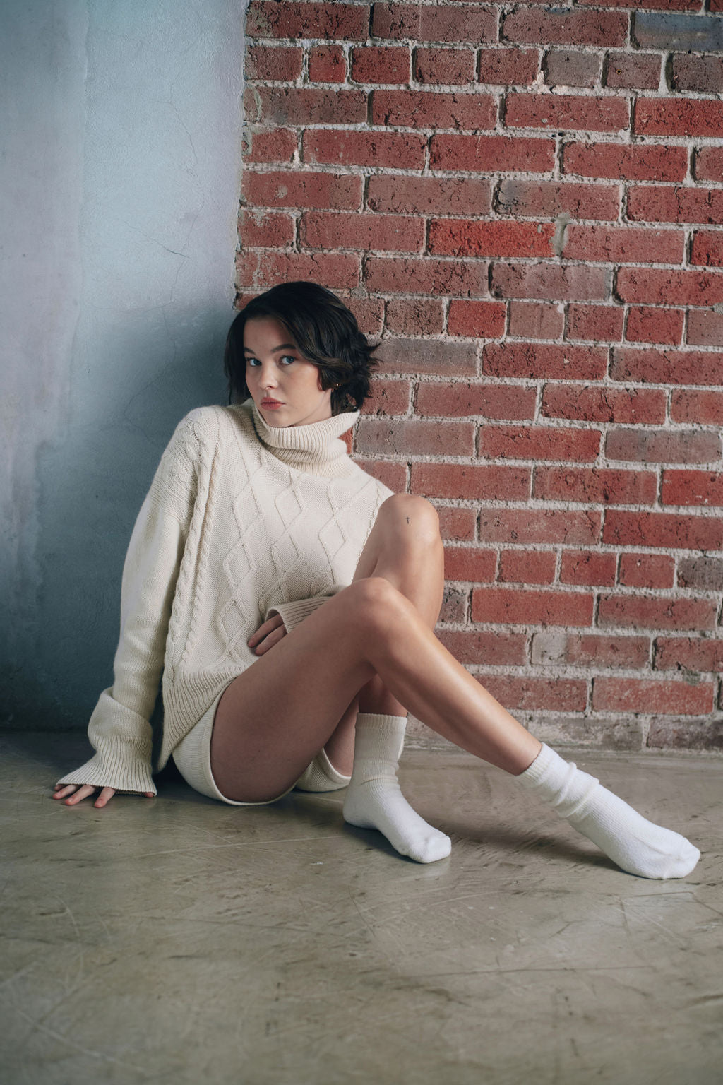 Model wearing oversized cable sweater in white alpaca wool, standing