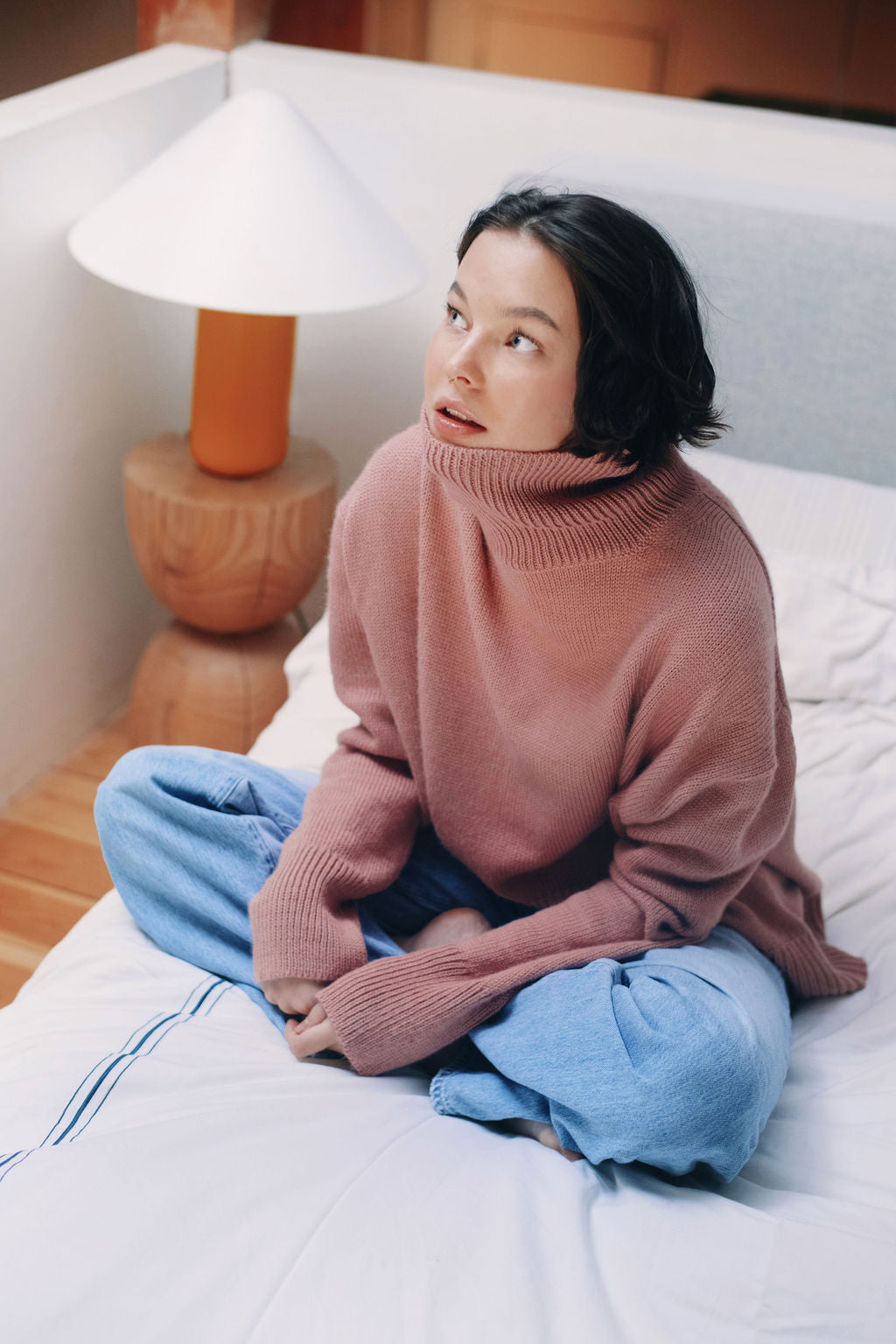 Model wearing oversized sweater in light pink alpaca wool, sitting
