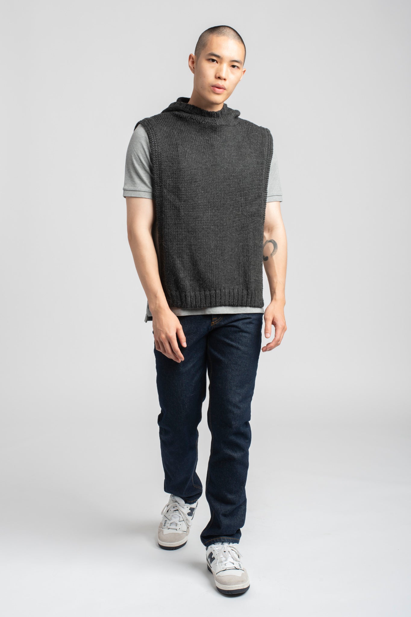 Model wearing poncho in dark grey alpaca wool, walking forward