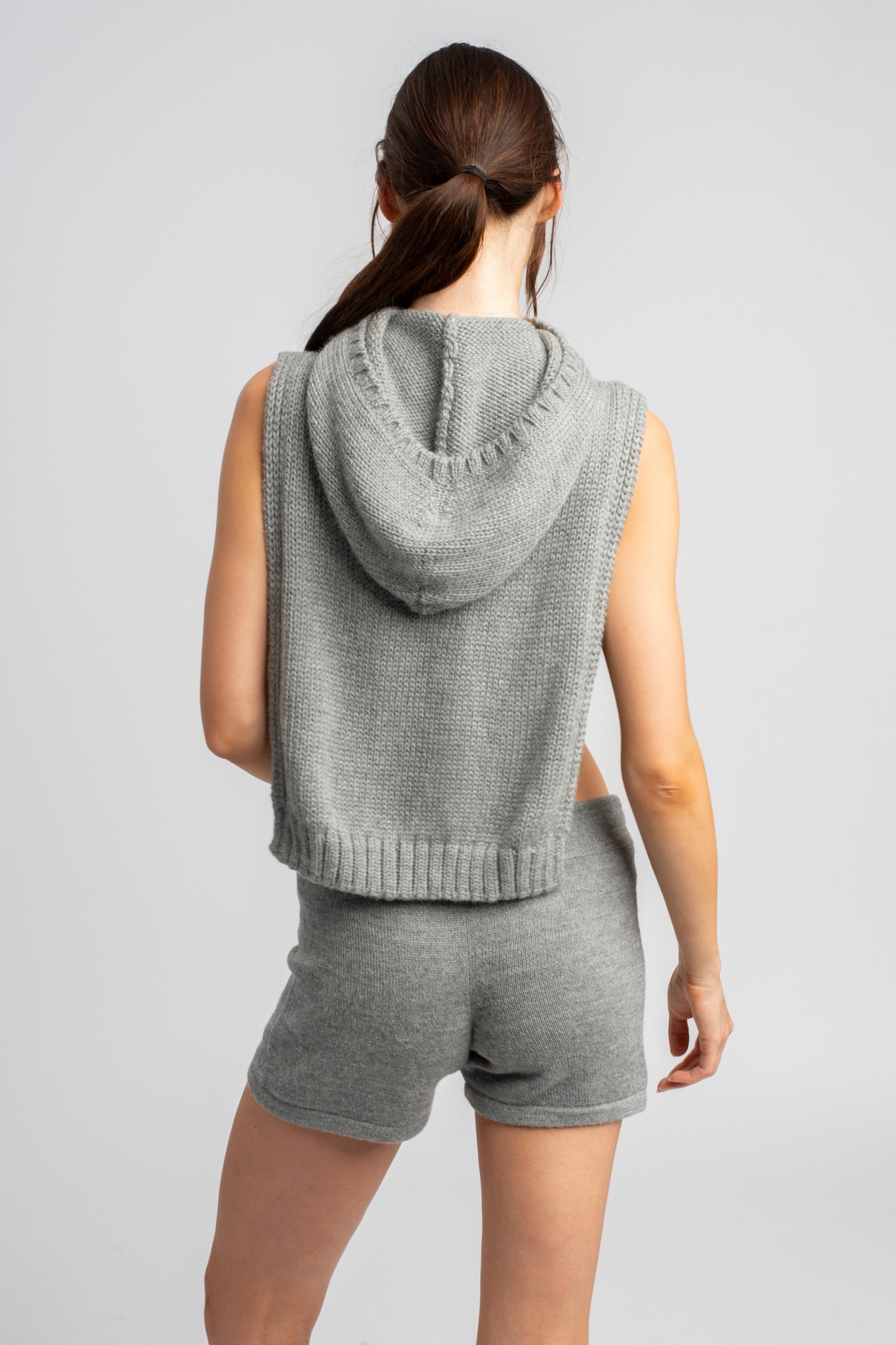 Model wearing poncho in light grey alpaca wool, back view close