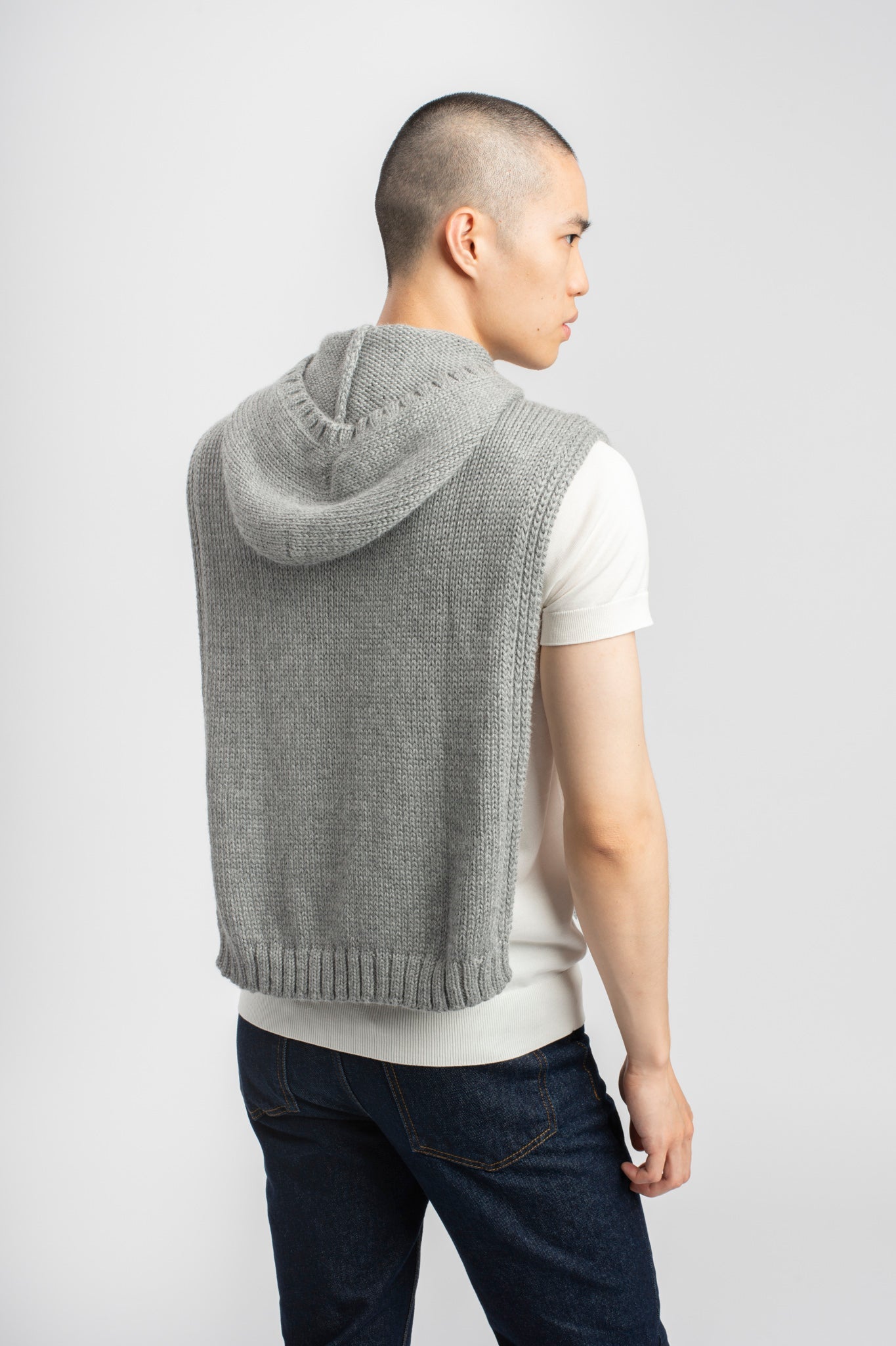 Model wearing poncho in light grey alpaca wool, back view of hood