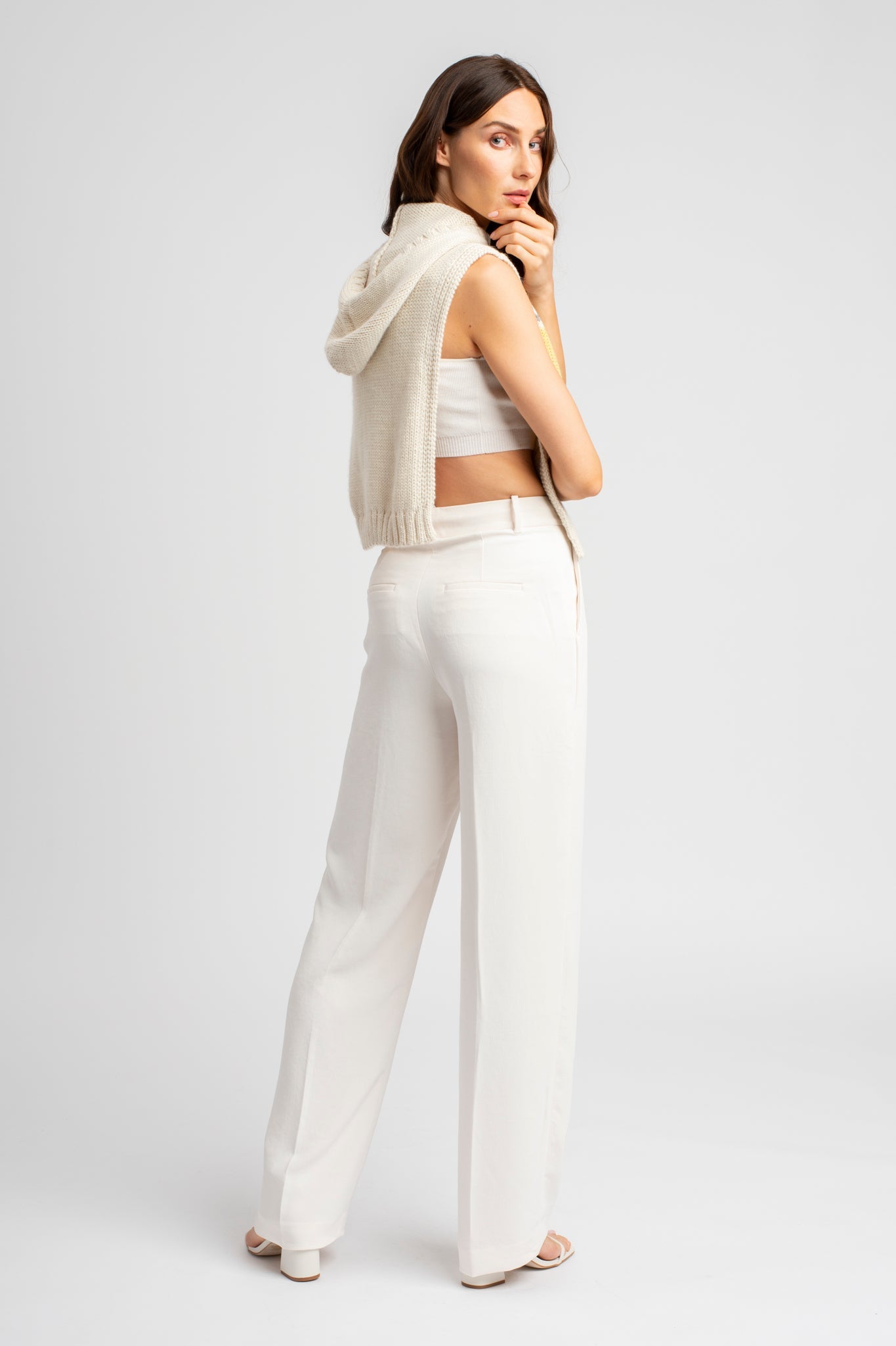 Model wearing poncho in white alpaca wool, side view standing up