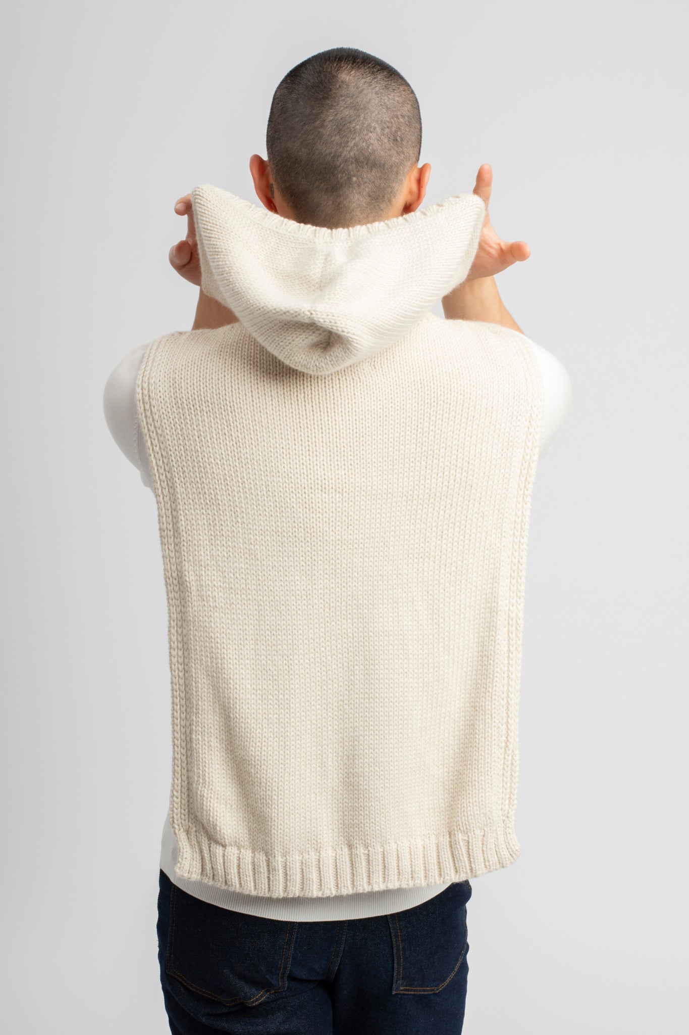 Model wearing poncho in white alpaca wool, back view hood close-up