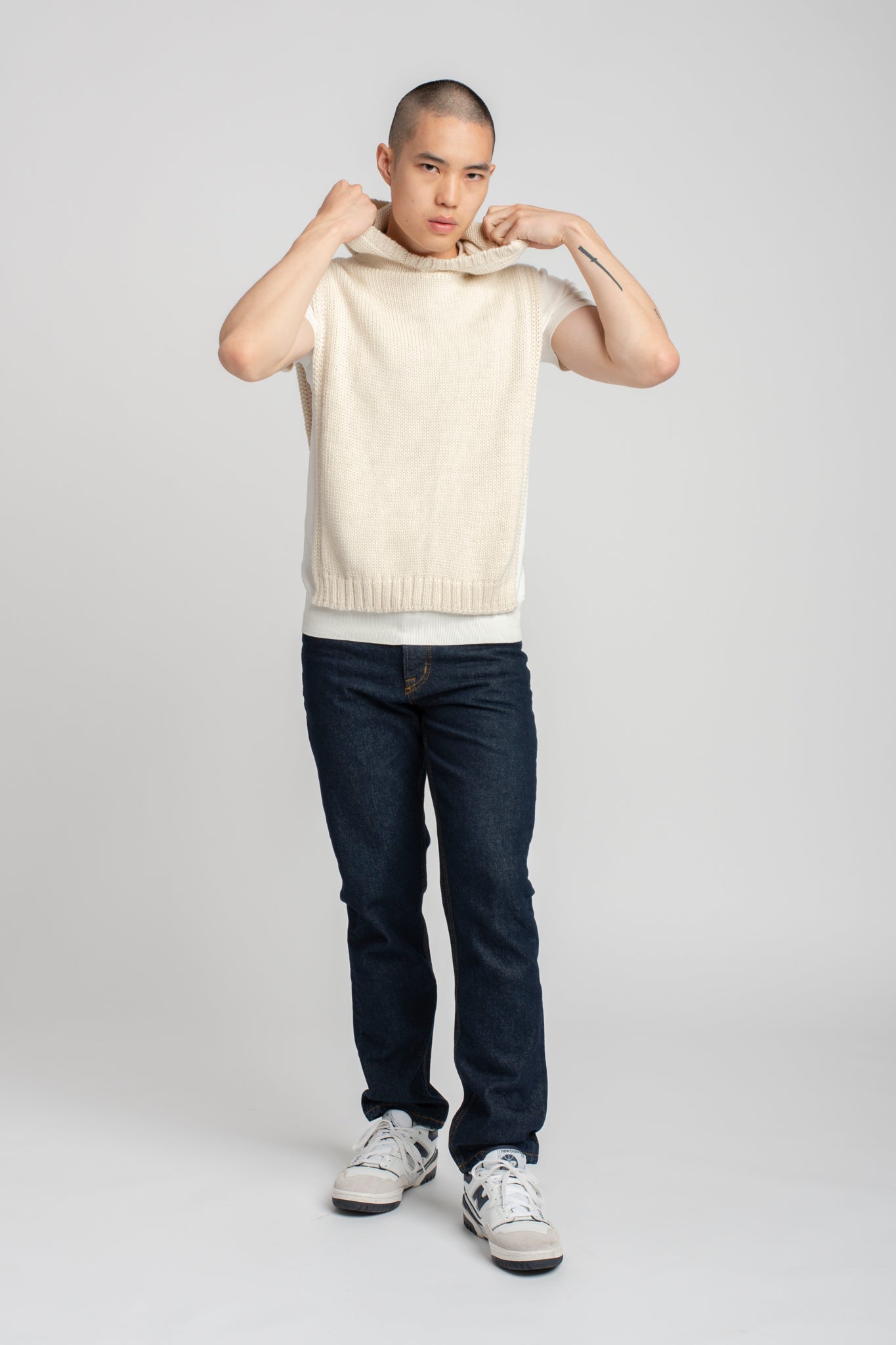 Model wearing poncho in white alpaca wool with black pants, back view