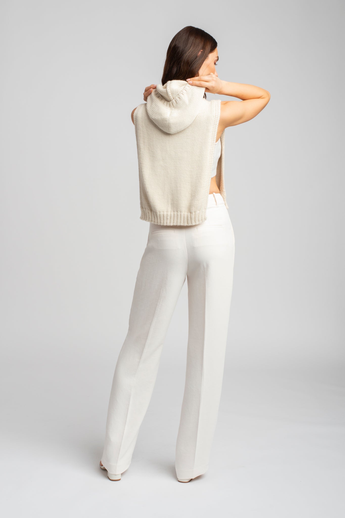 Model wearing poncho in white alpaca wool, standing back view