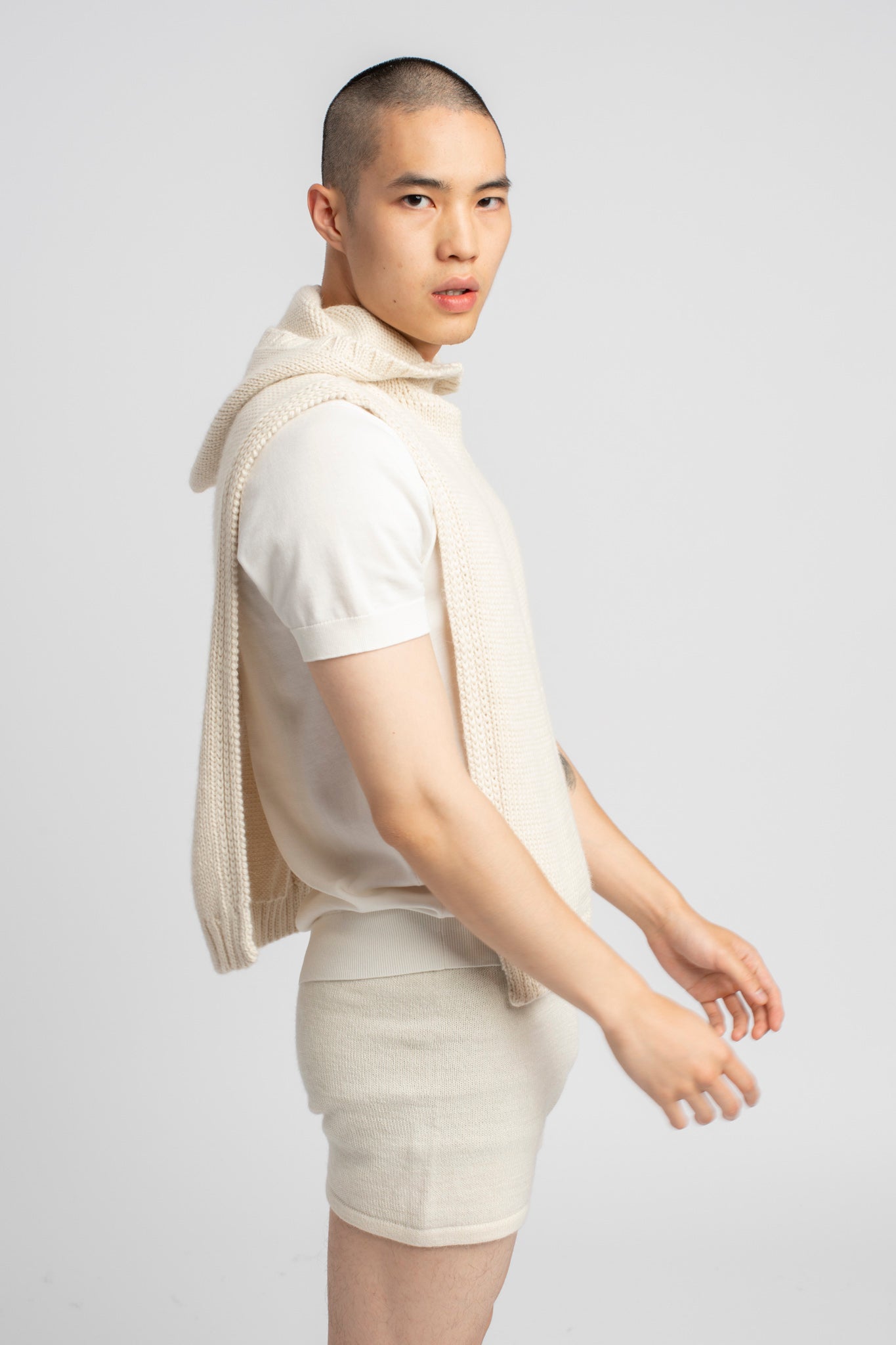 Model wearing poncho in white alpaca wool, side view close-up
