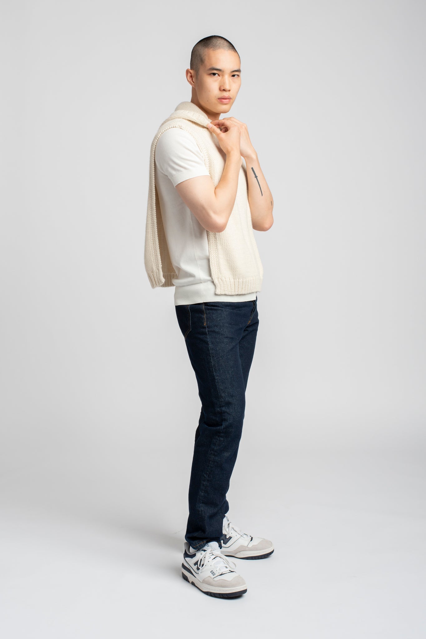 Model wearing poncho in white alpaca wool, side view standing