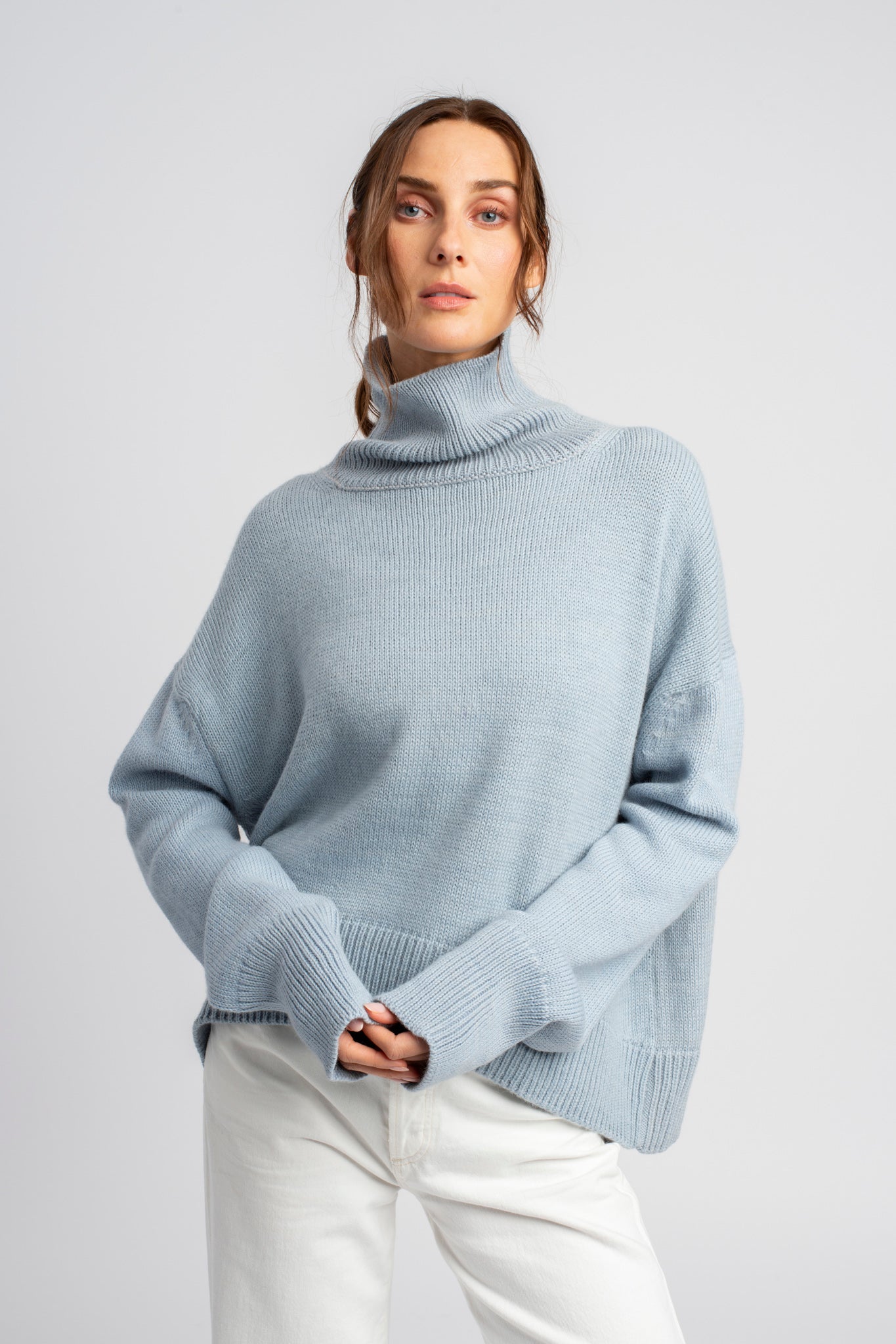 Model wearing turtleneck oversized sweater in blue alpaca wool, side