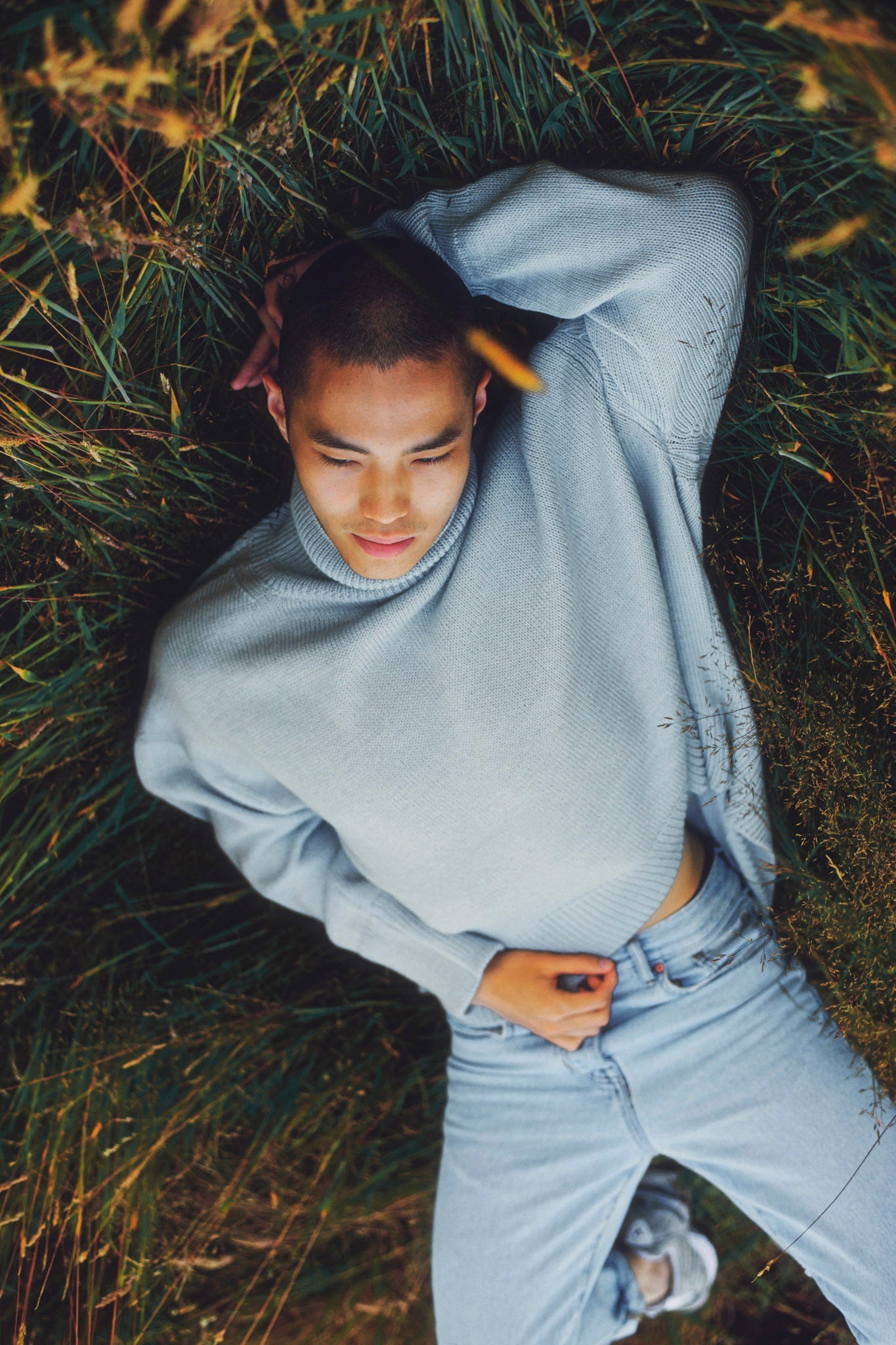 Model wearing turtleneck oversized sweater in blue alpaca wool, laying down