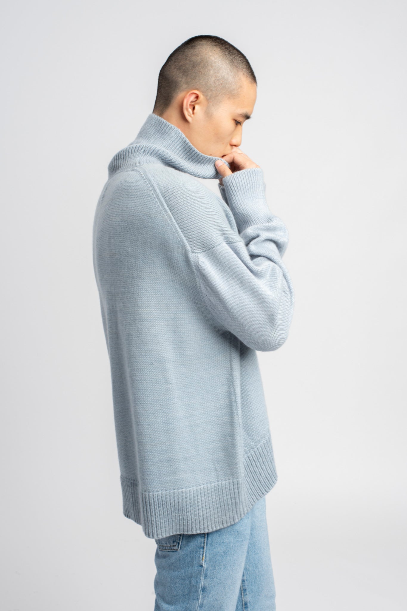 Model wearing turtleneck oversized sweater in blue alpaca wool, side view