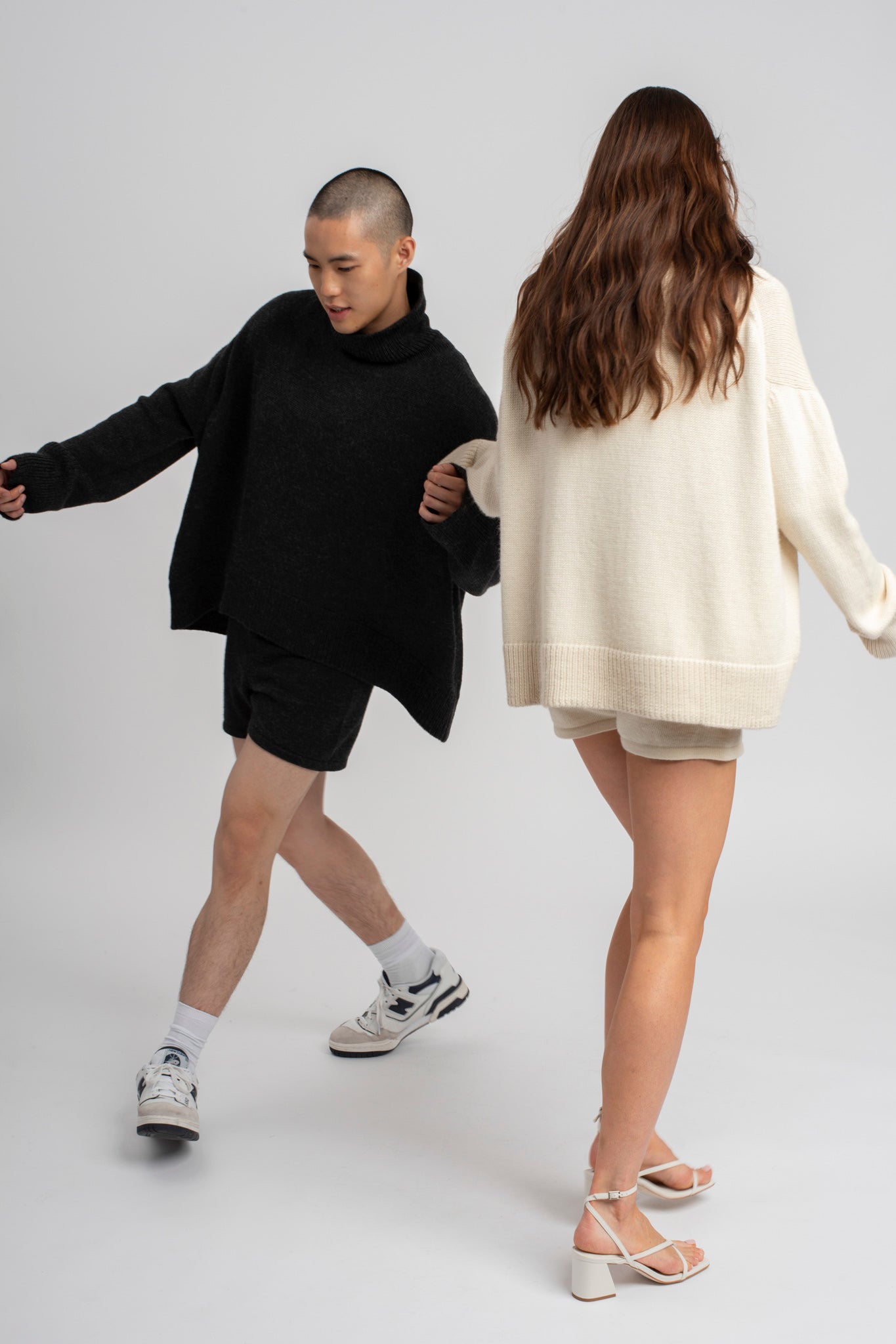 Models wearing turtleneck oversized sweater in dark grey and white alpaca wool, walking
