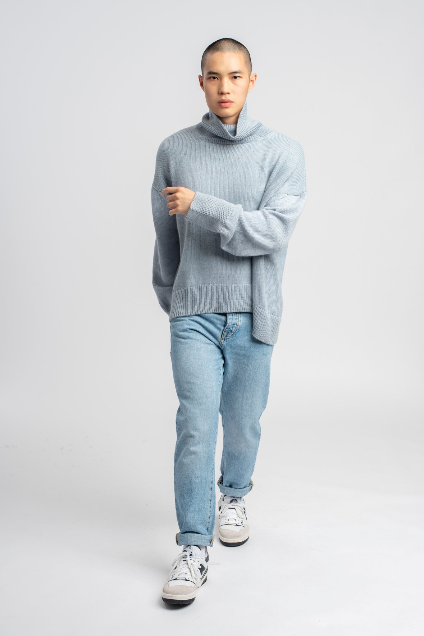 Model wearing turtleneck oversized sweater in blue alpaca wool, walking