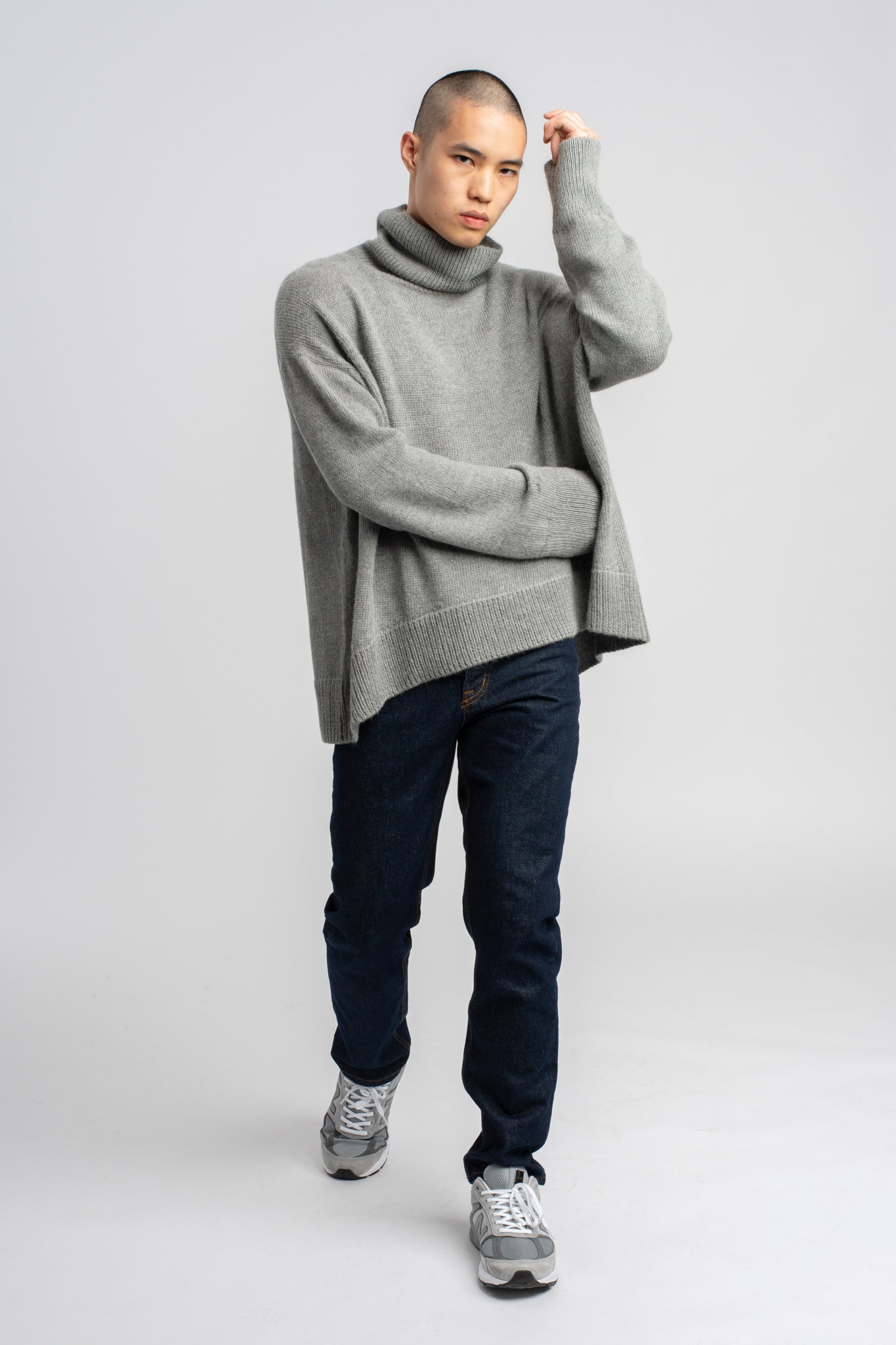 Model wearing turtleneck oversized sweater in light grey alpaca wool, walking