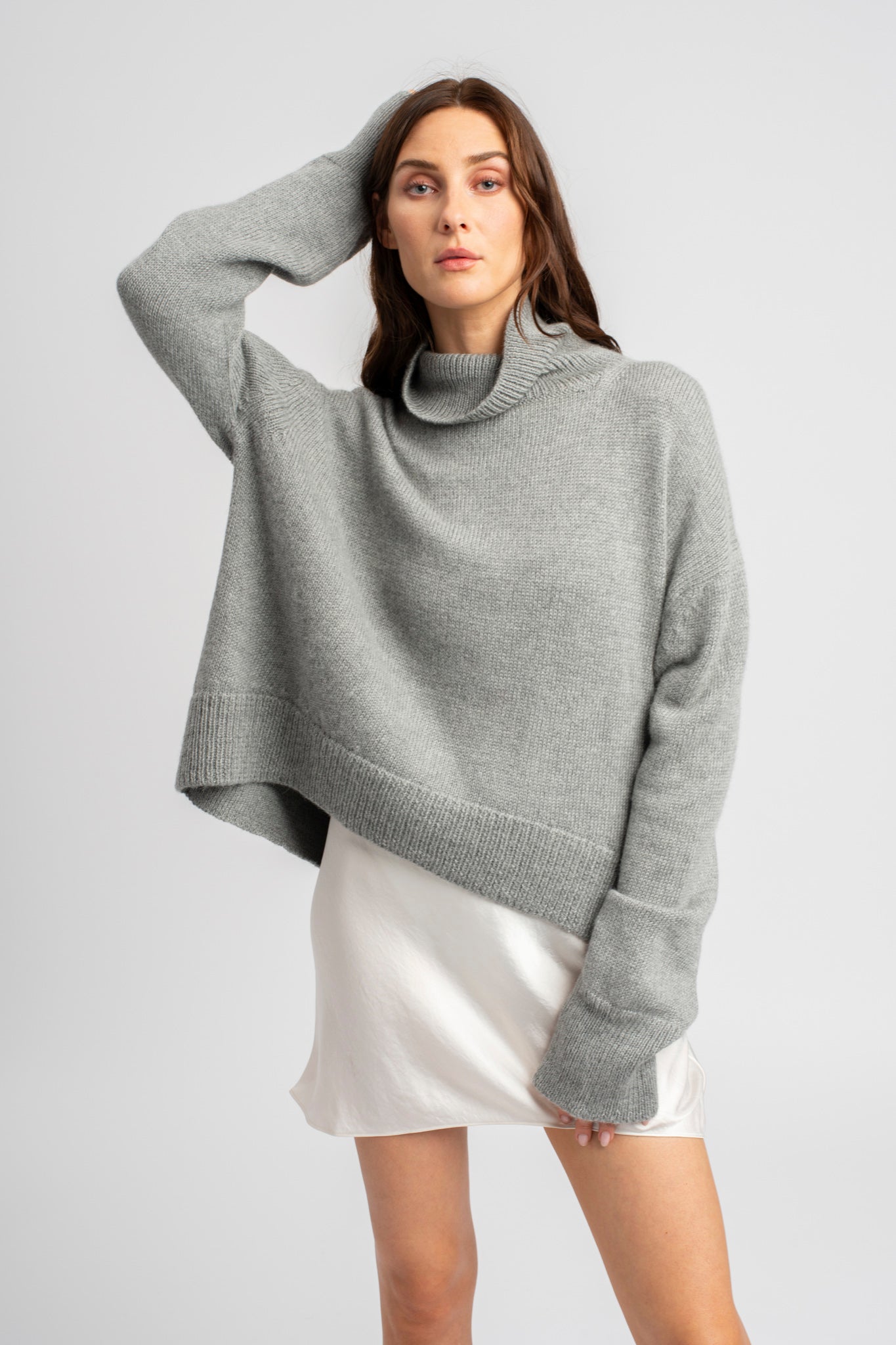 Model wearing turtleneck oversized sweater in light grey alpaca wool, front