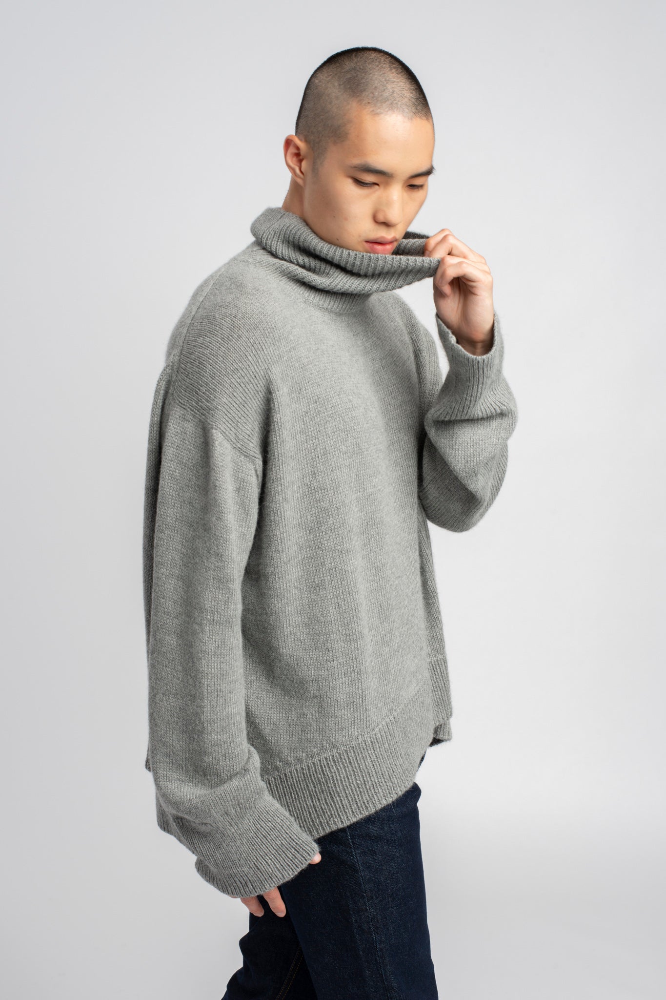 Model wearing turtleneck oversized sweater in light grey alpaca wool, side
