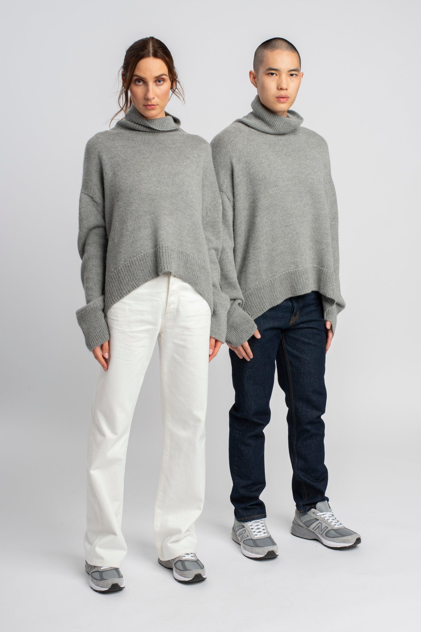 Models wearing turtleneck oversized sweater in light grey alpaca wool, side by side