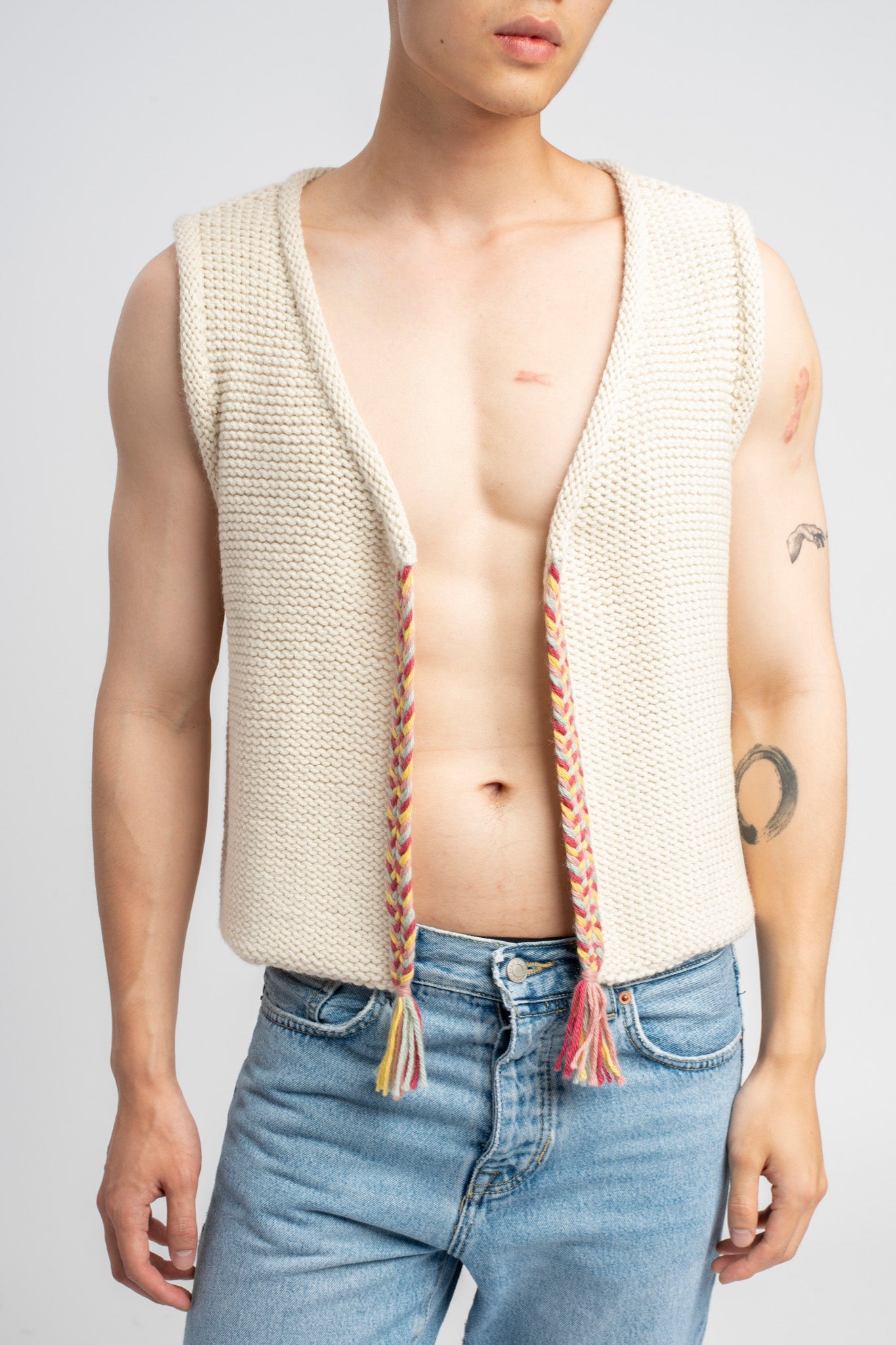 Model wearing white sweater knit vest in alpaca wool, standing outside, front close-up