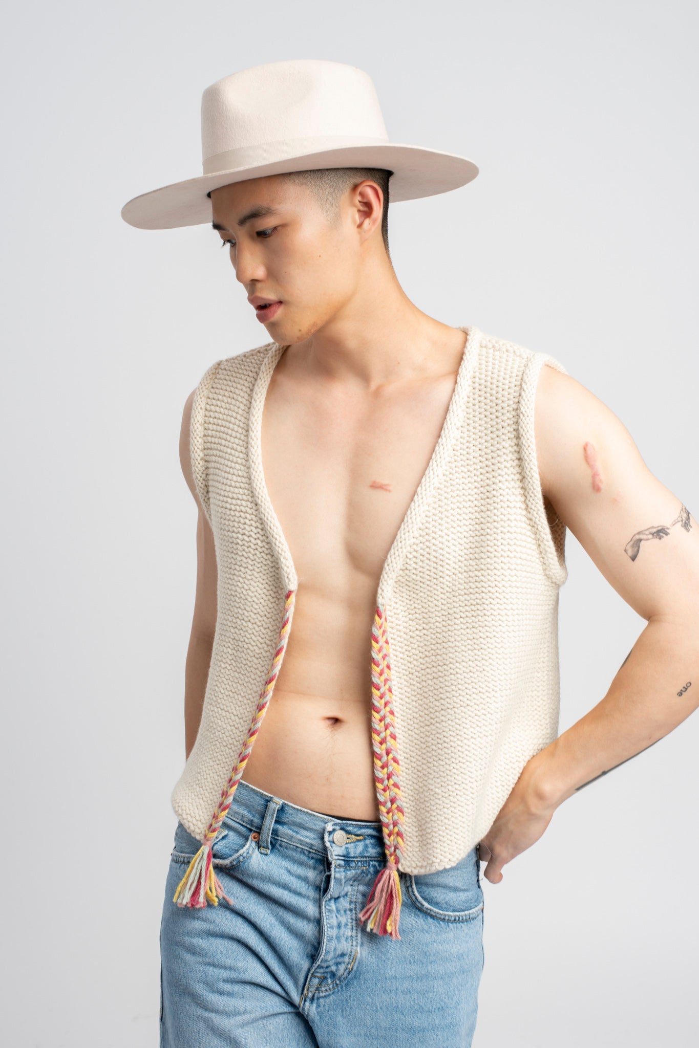 Model wearing white sweater knit vest in alpaca wool, standing outside, front view