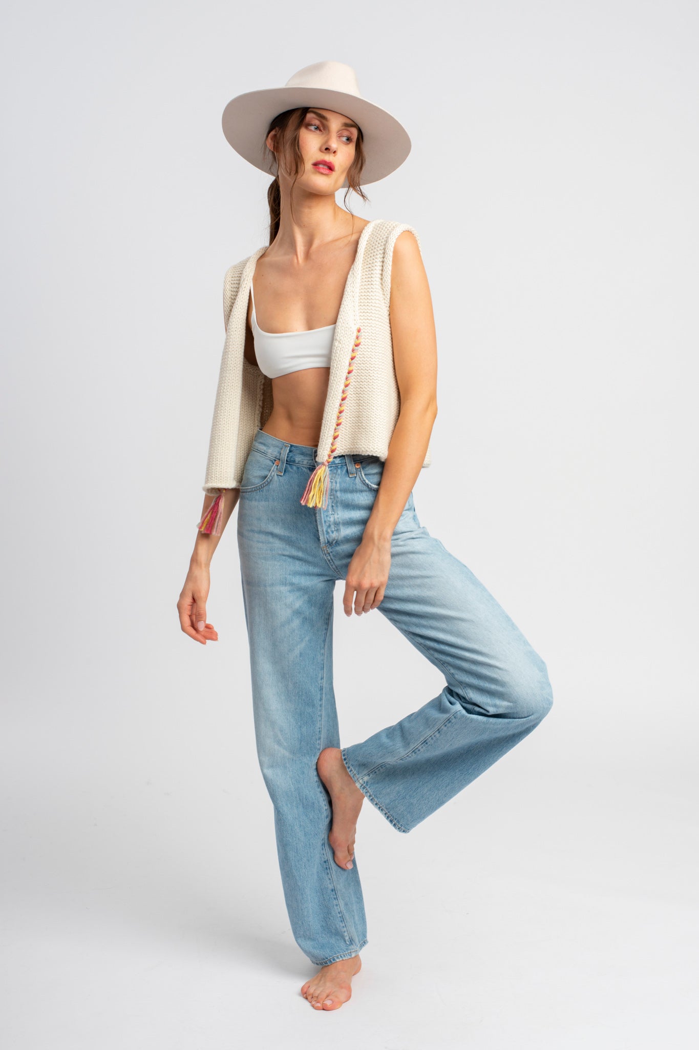 Model wearing white sweater knit vest in alpaca wool, standing outside, standing