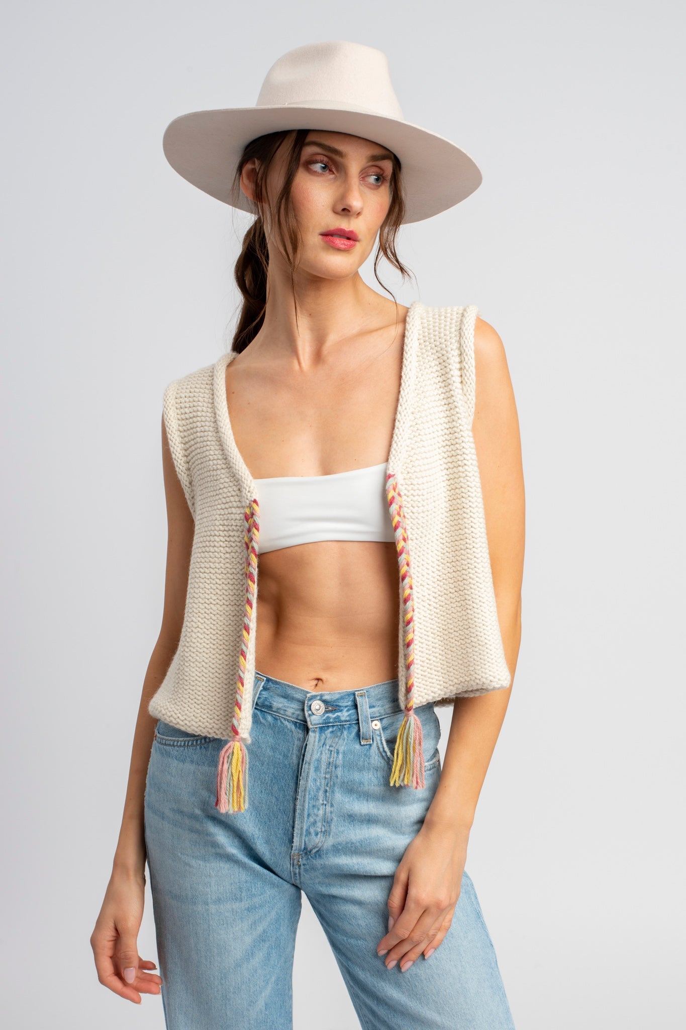 Model wearing white sweater knit vest in alpaca wool, standing outside, front