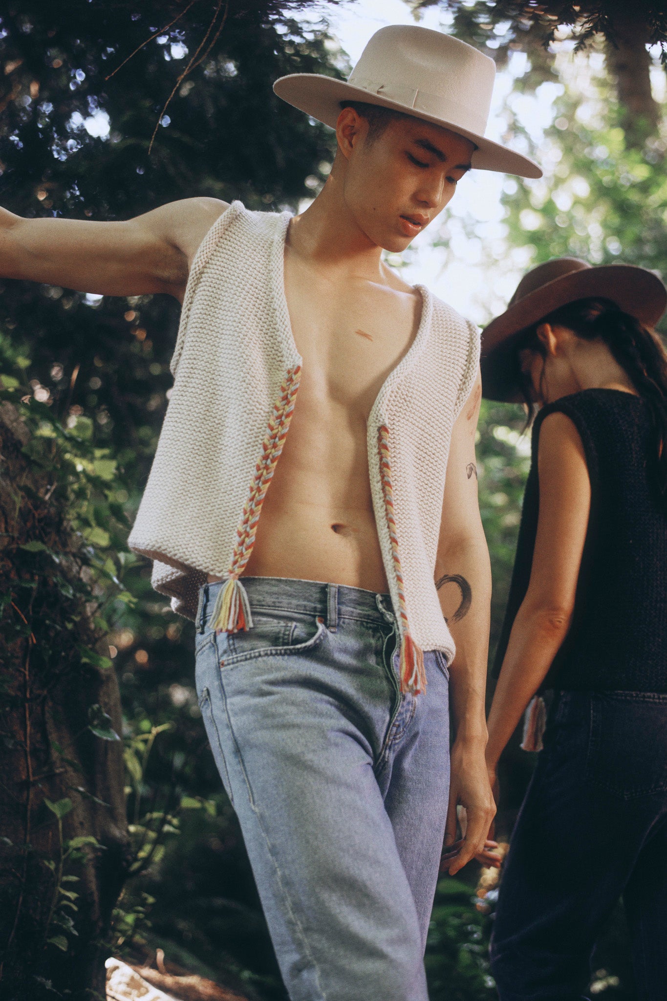 Model wearing white sweater knit vest in alpaca wool, standing outside, front
