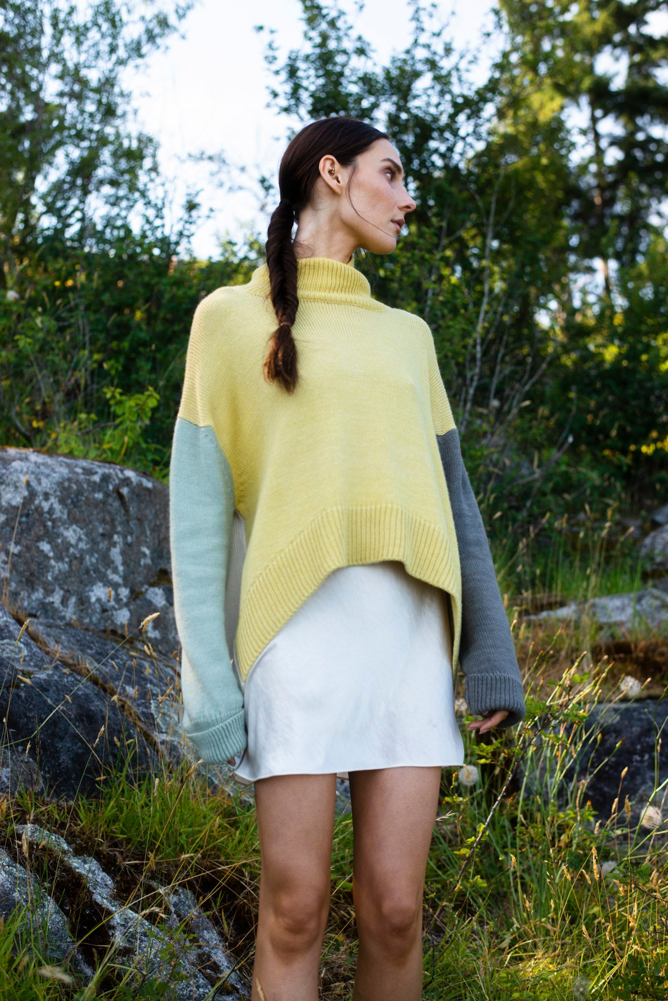 Model wearing turtleneck oversized sweater in multi-color yellow alpaca wool, standing