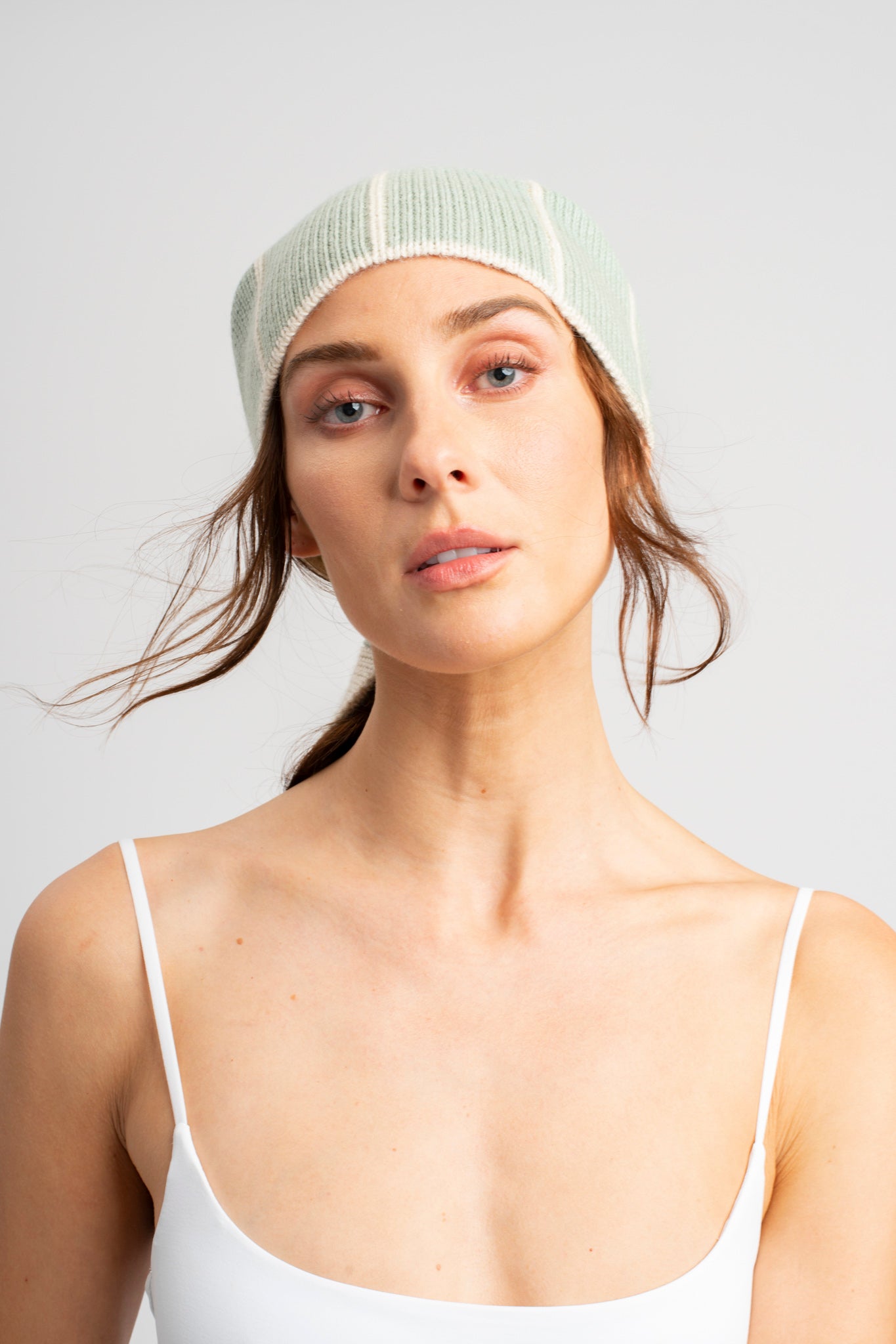Model wearing knitwear headscarf alpaca wool in white & sage reversible stripes