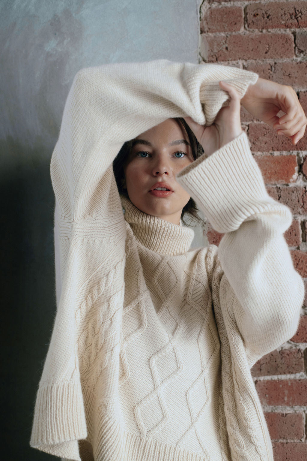 Model wearing oversized cable sweater in white alpaca wool, front close-up
