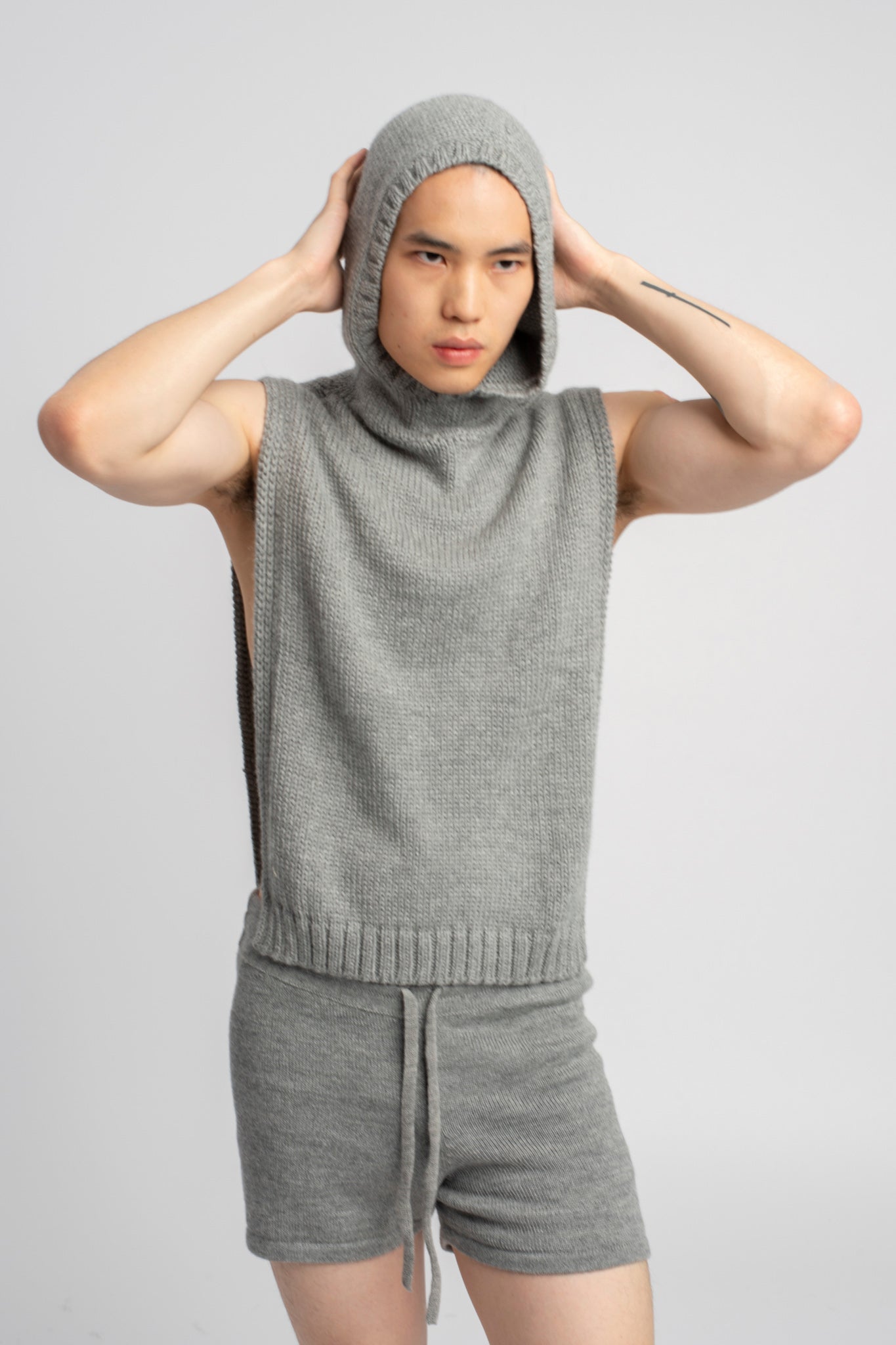 Model wearing poncho in light grey alpaca wool, front wearing hood