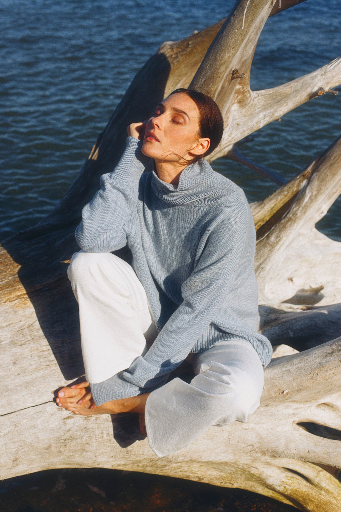 Model wearing turtleneck oversized sweater in blue alpaca wool, sitting