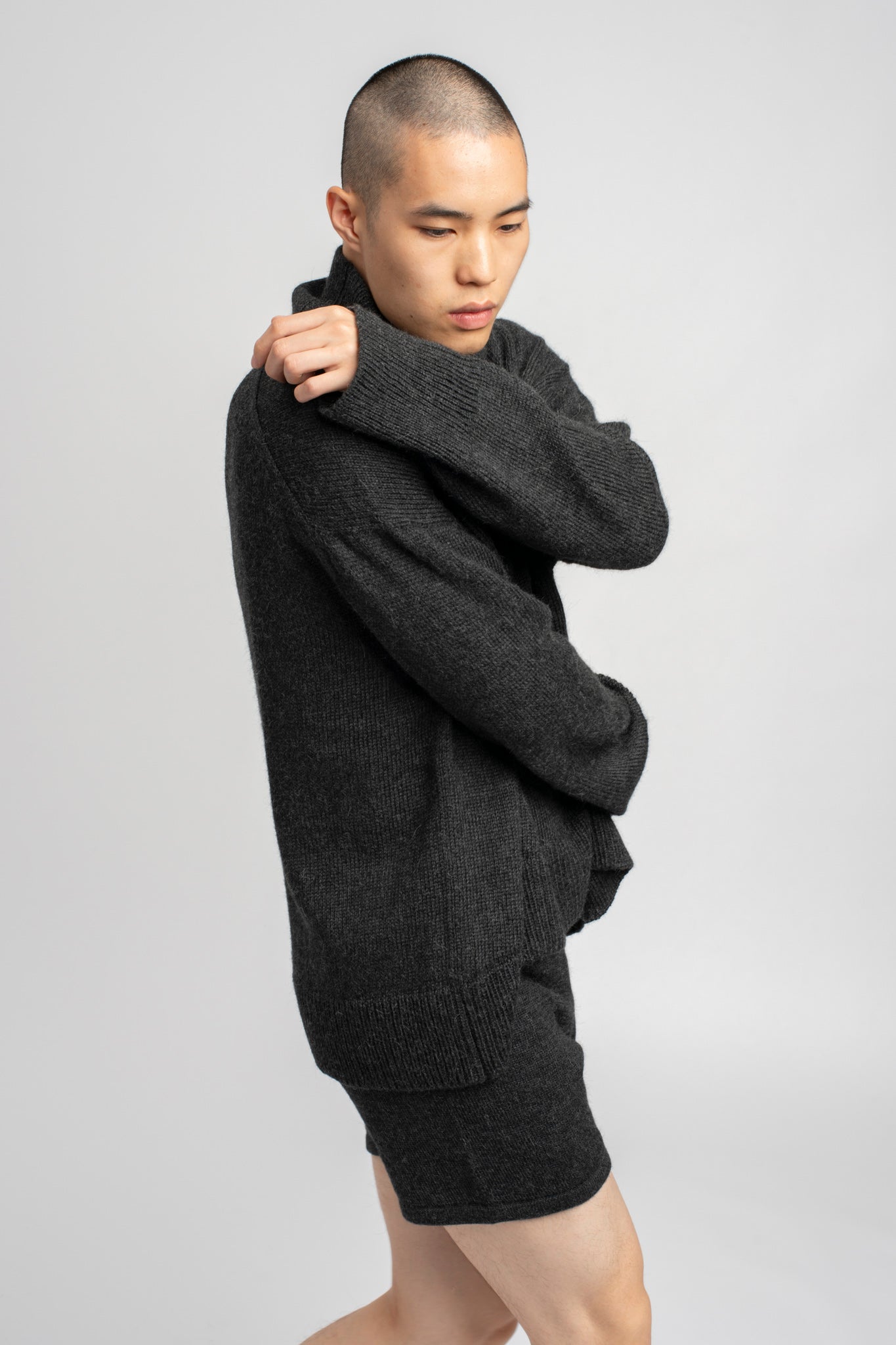 Model wearing turtleneck oversized sweater in dark grey alpaca wool, side