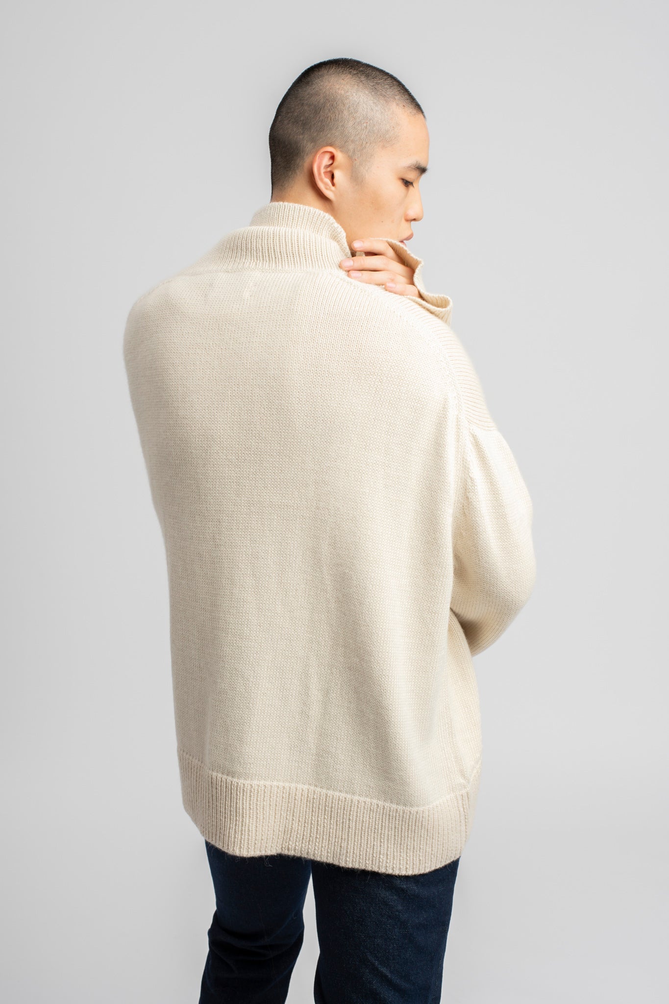 Model wearing turtleneck oversized sweater in white alpaca wool, back