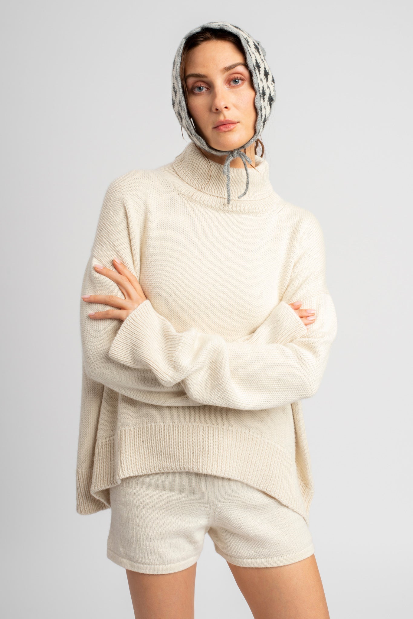 Model wearing turtleneck oversized sweater in white alpaca wool, arms crossed