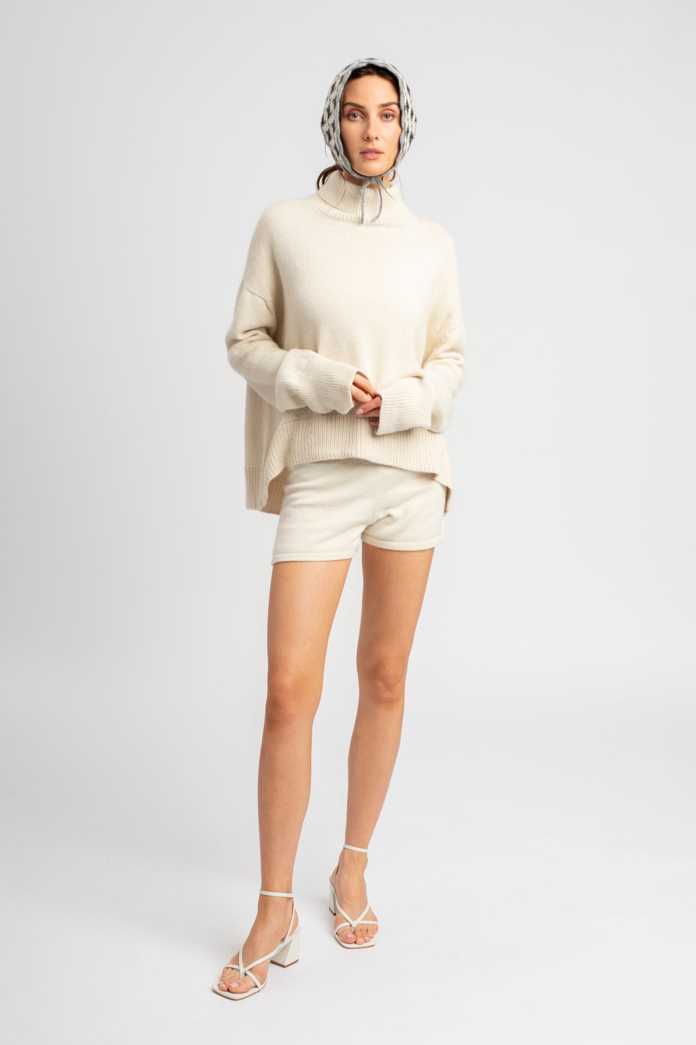 Model wearing turtleneck oversized sweater in white alpaca wool, front standing