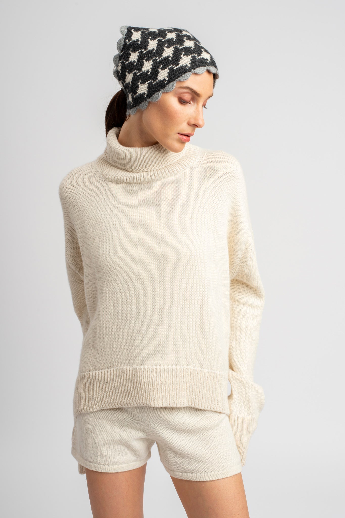 Model wearing turtleneck oversized sweater in white alpaca wool with headscarf