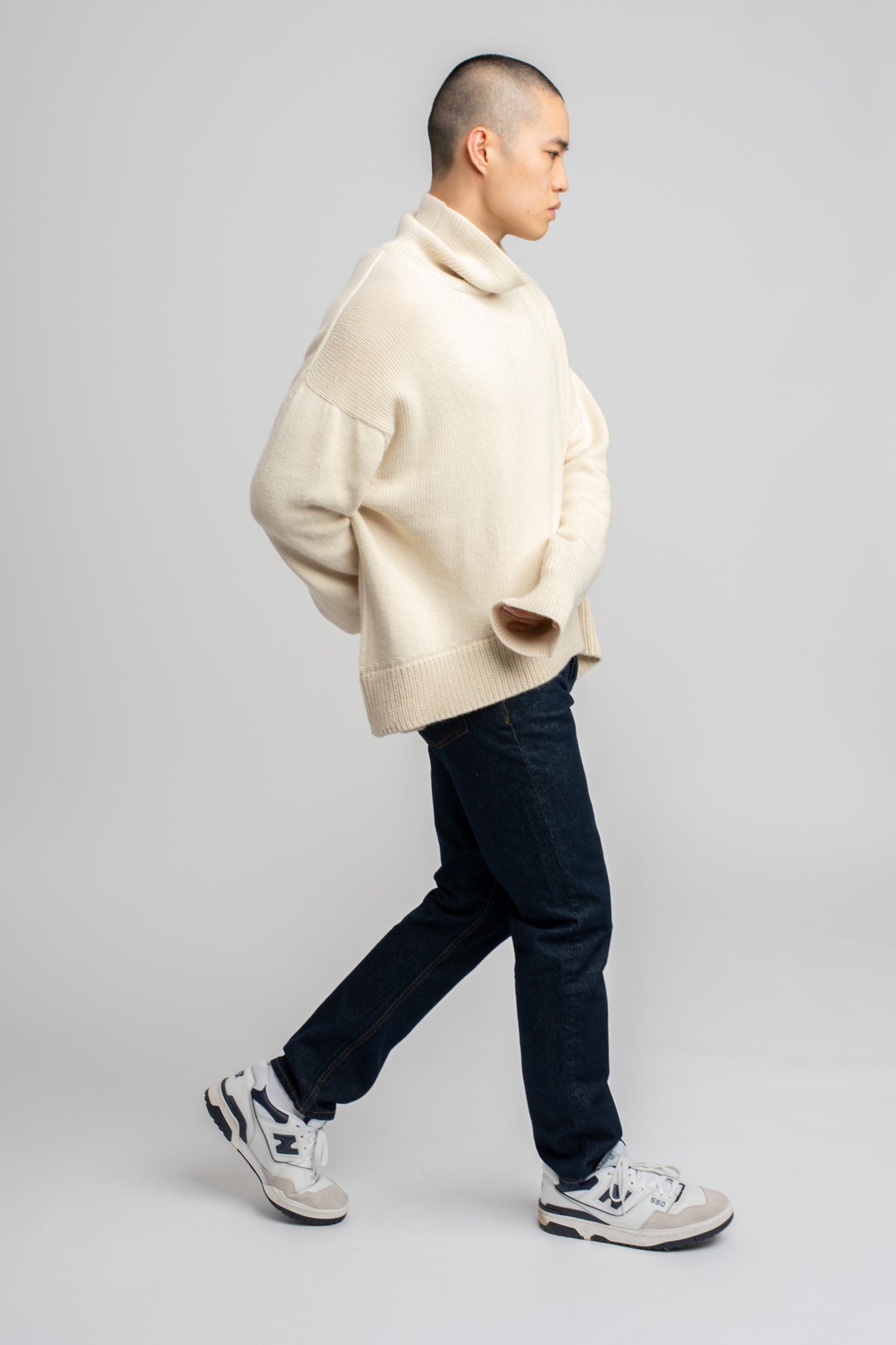 Model wearing turtleneck oversized sweater in white alpaca wool, standing side
